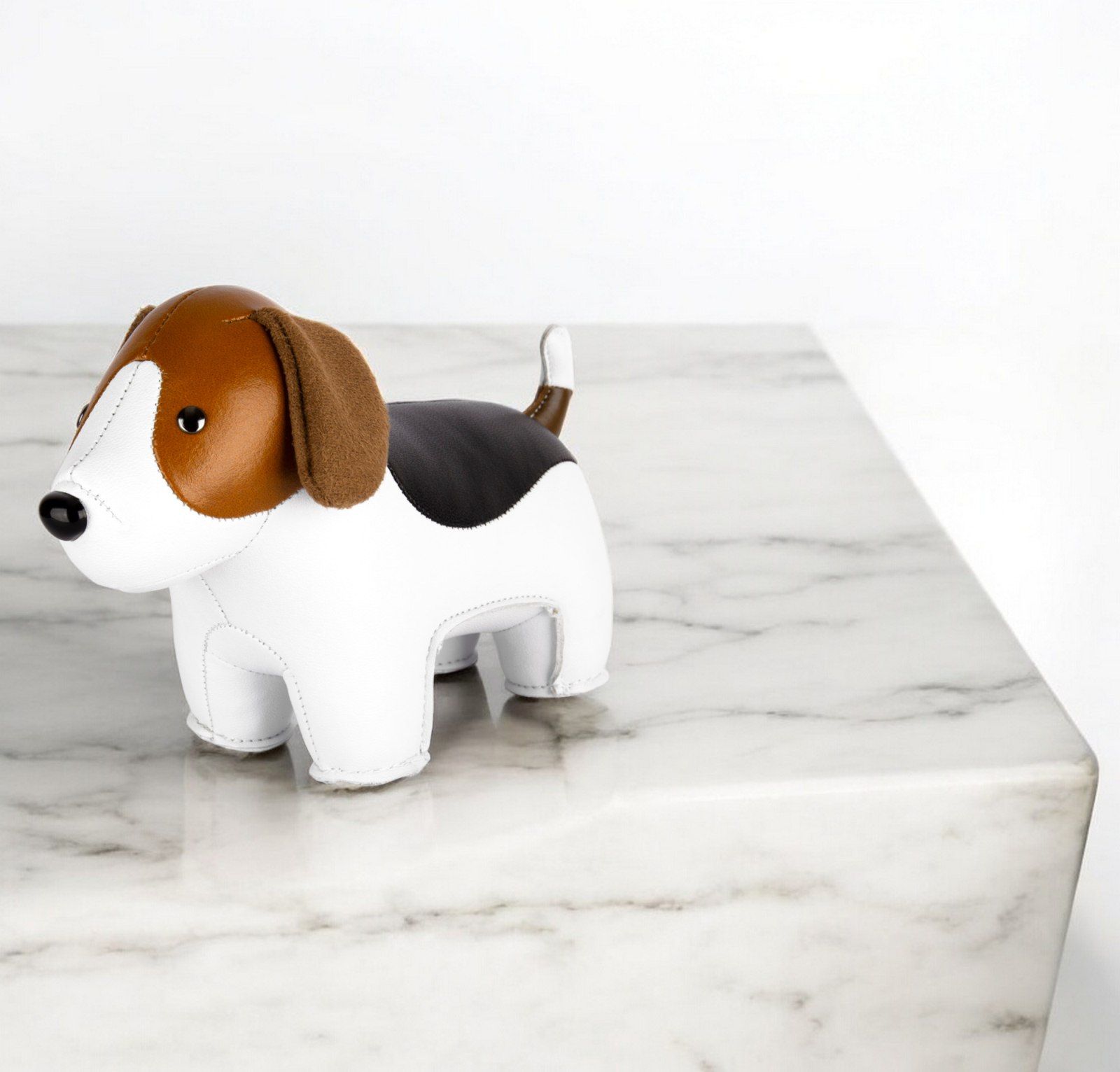 Briefbeschwerer Beagle Züny aus Lederimitat, weiß, braun und schwarz, auf einer Marmoroberfläche.