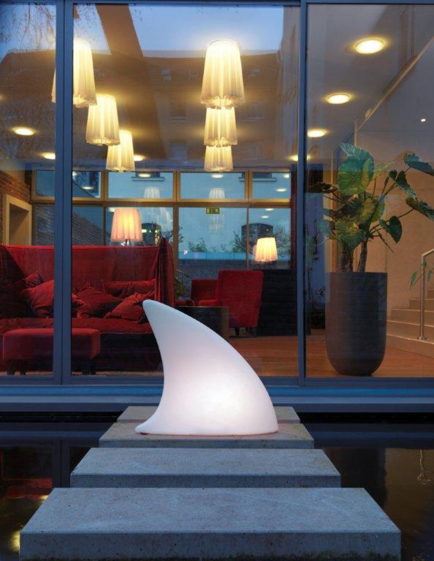 Moree Shark Haifischflosse Bodenleuchte, weiße LED Lampe in Haifischflossenform auf Steinstufen im Außenbereich.