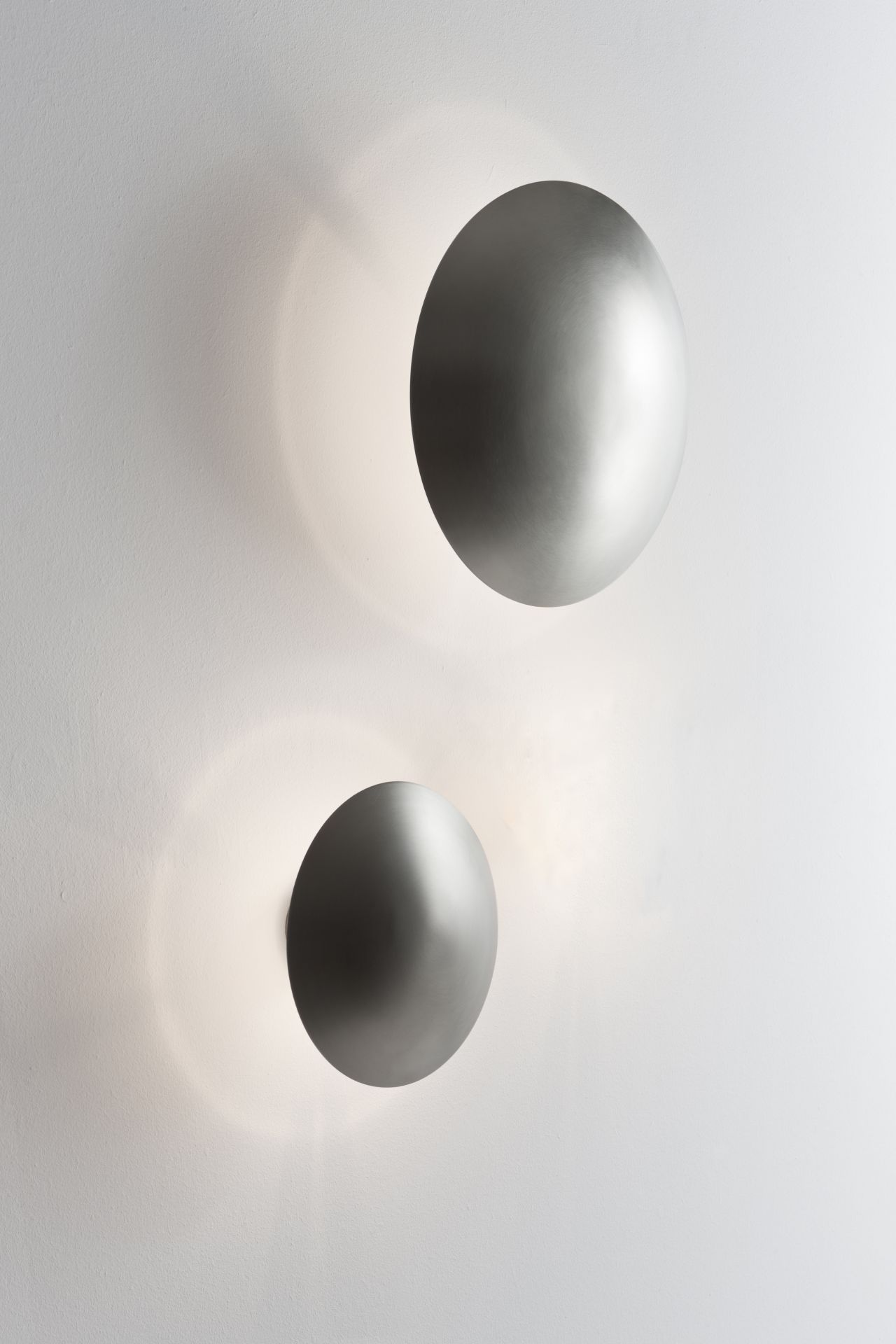 Zwei silberne Disco Wandleuchten von Santa & Cole an einer weißen Wand.