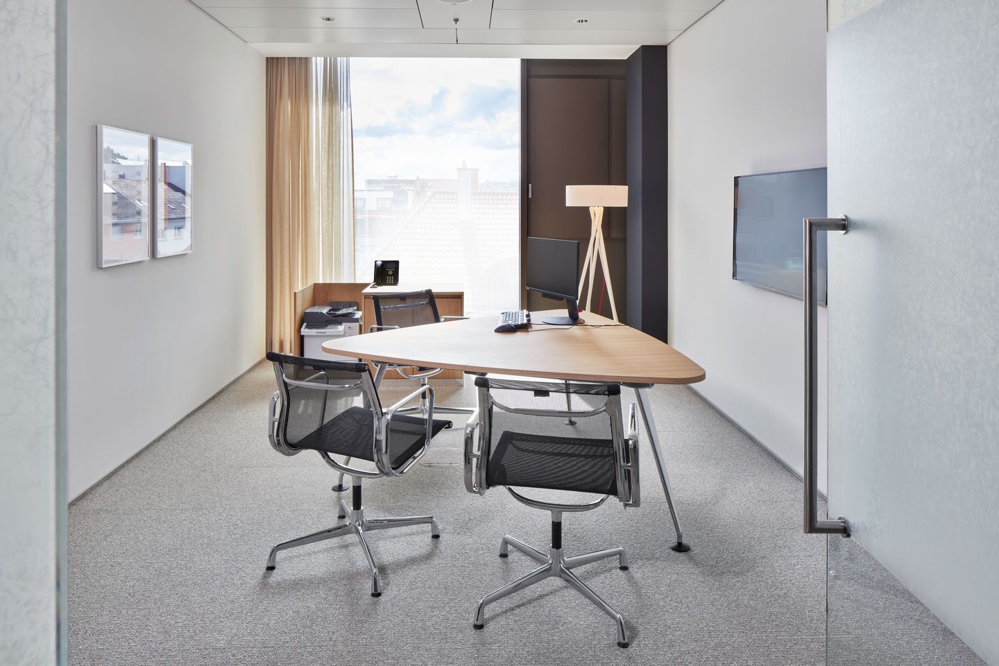Büro mit dreieckigem Holztisch und zwei Aluminium Chair EA 104 / EA104 Stühlen von Vitra.