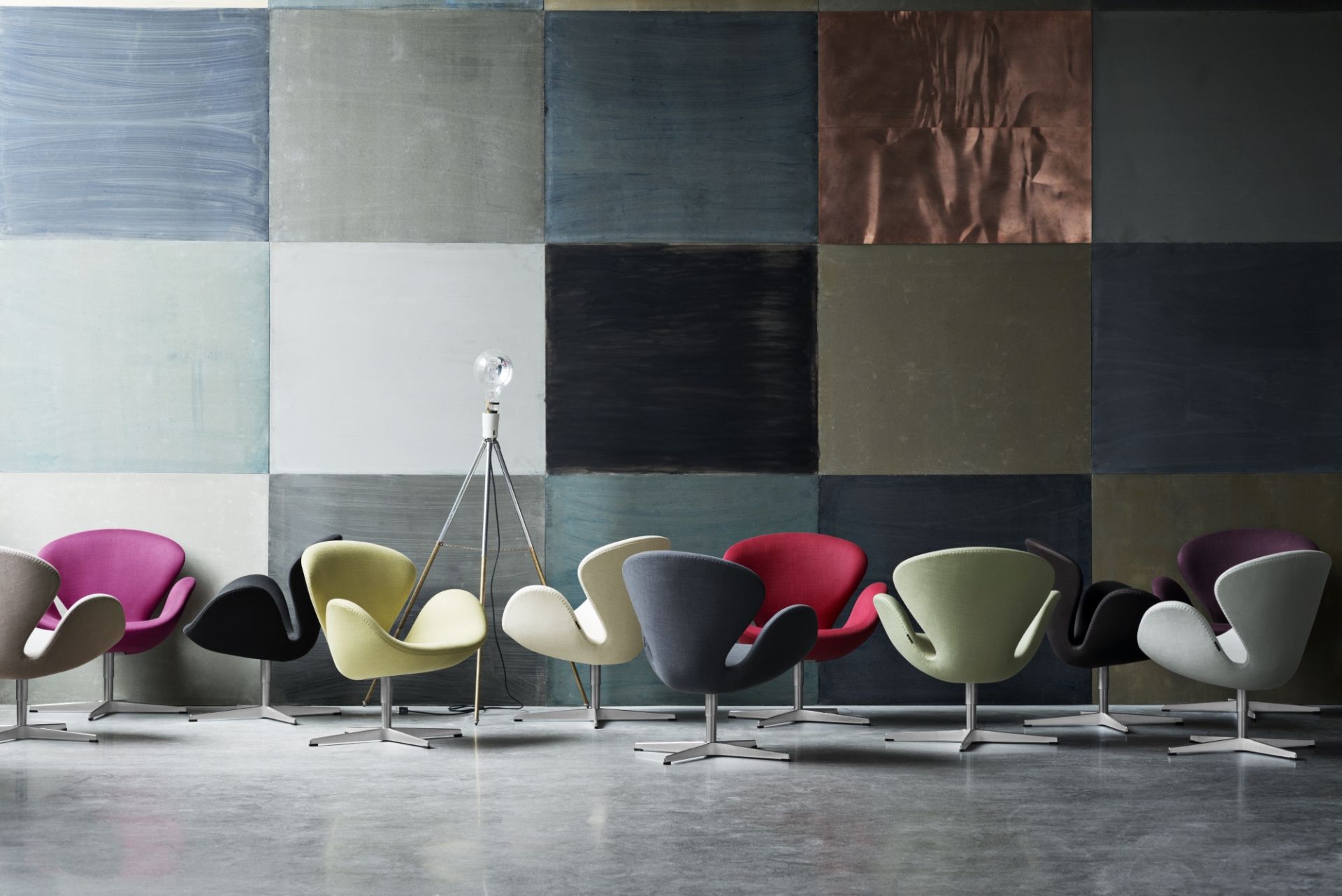 Fritz Hansen Schwan Sessel in verschiedenen Farben vor einer Wand mit Farbquadraten.