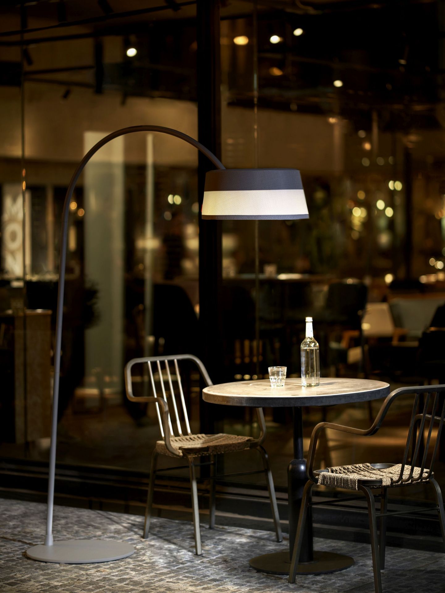 ISA-BELLE Solarleuchte als Bogenlampe über Tisch mit Stühlen, stimmungsvolle Gartenbeleuchtung für den Außenbereich.
