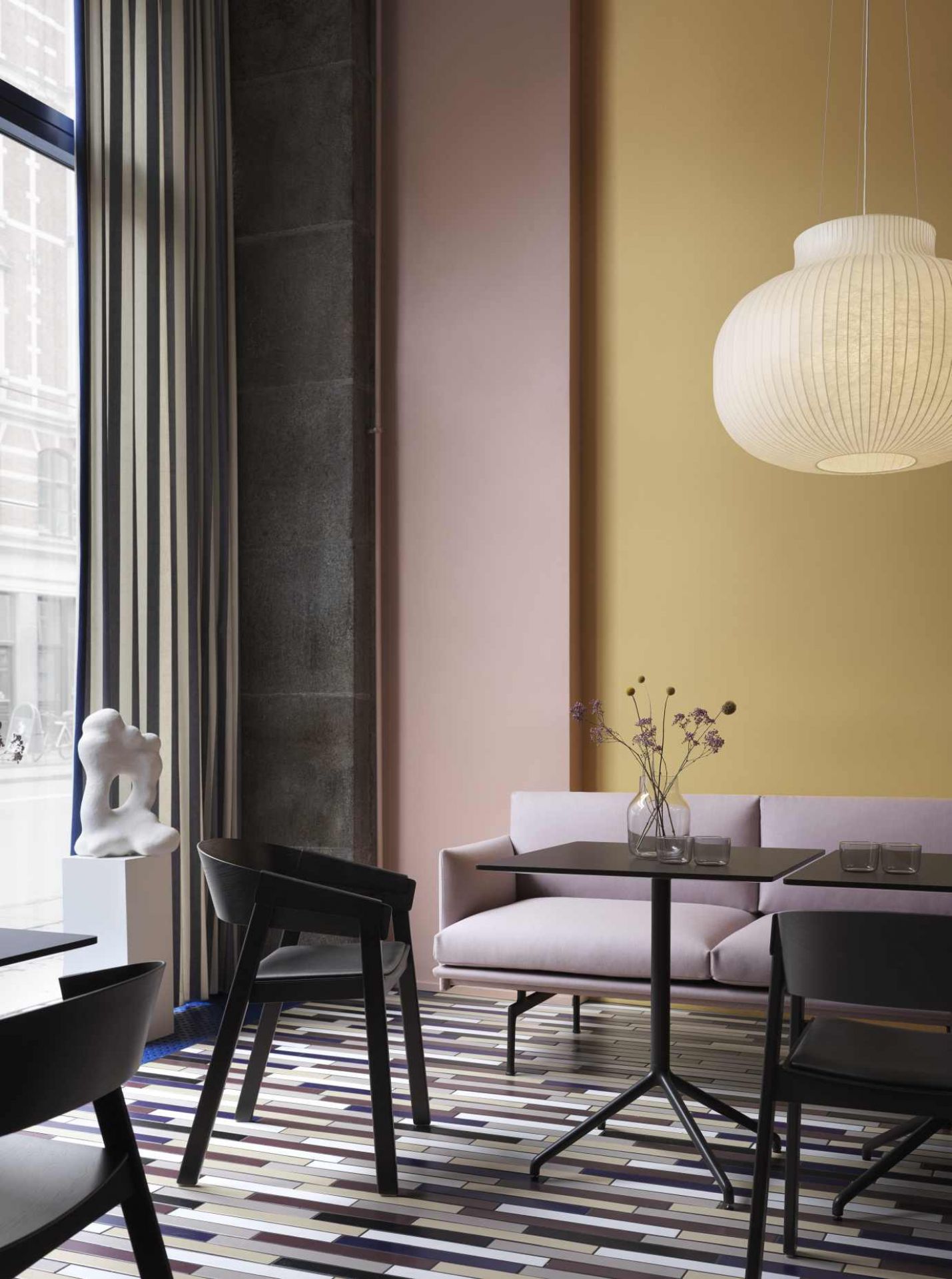 Helle Muuto Strand Pendelleuchte über Esstisch mit Sofa und Stühlen in modernem Interieur.