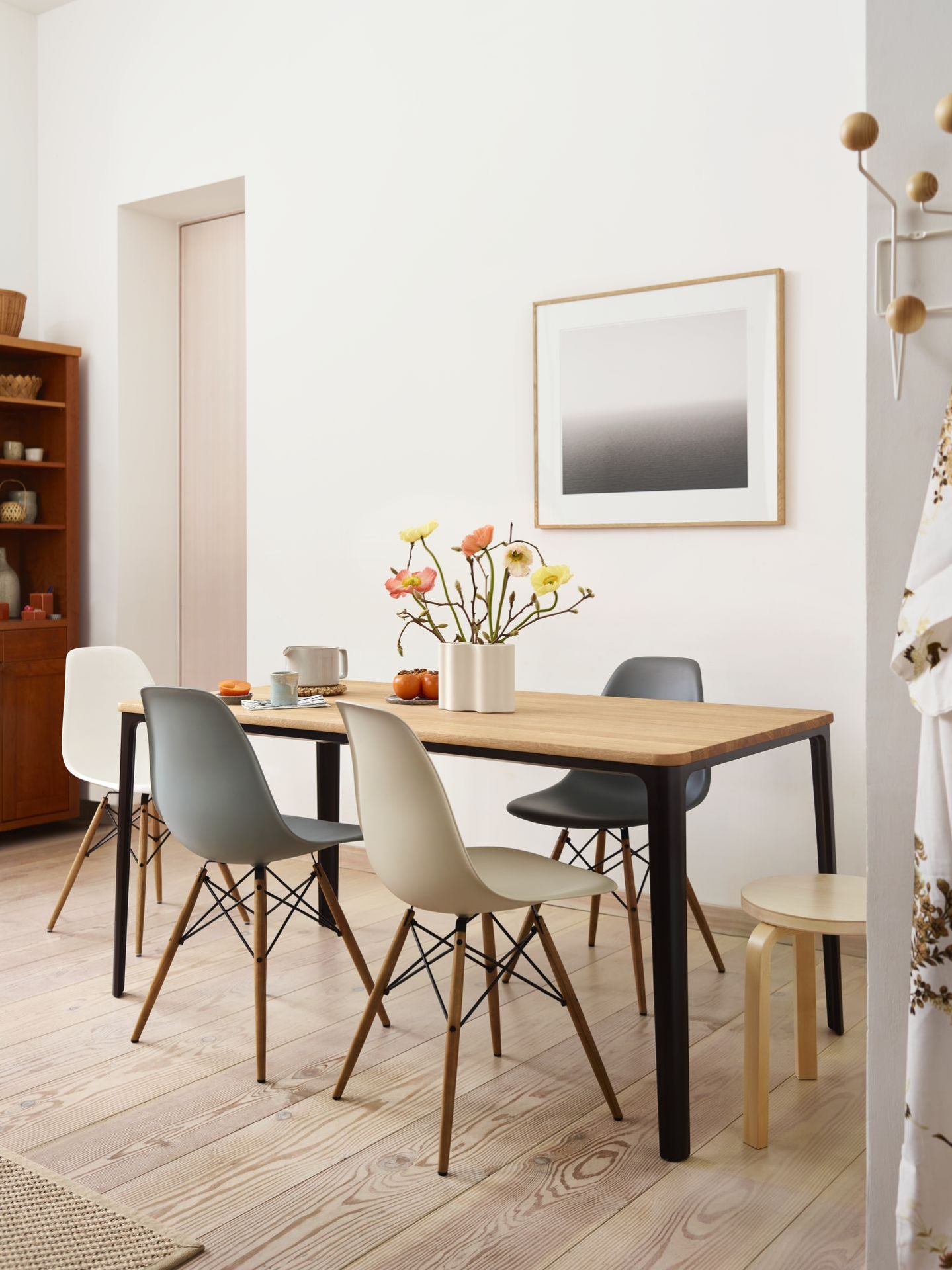 Esszimmer mit Holztisch und vier Vitra Eames Fiberglass Chairs DSW in verschiedenen Farben.
