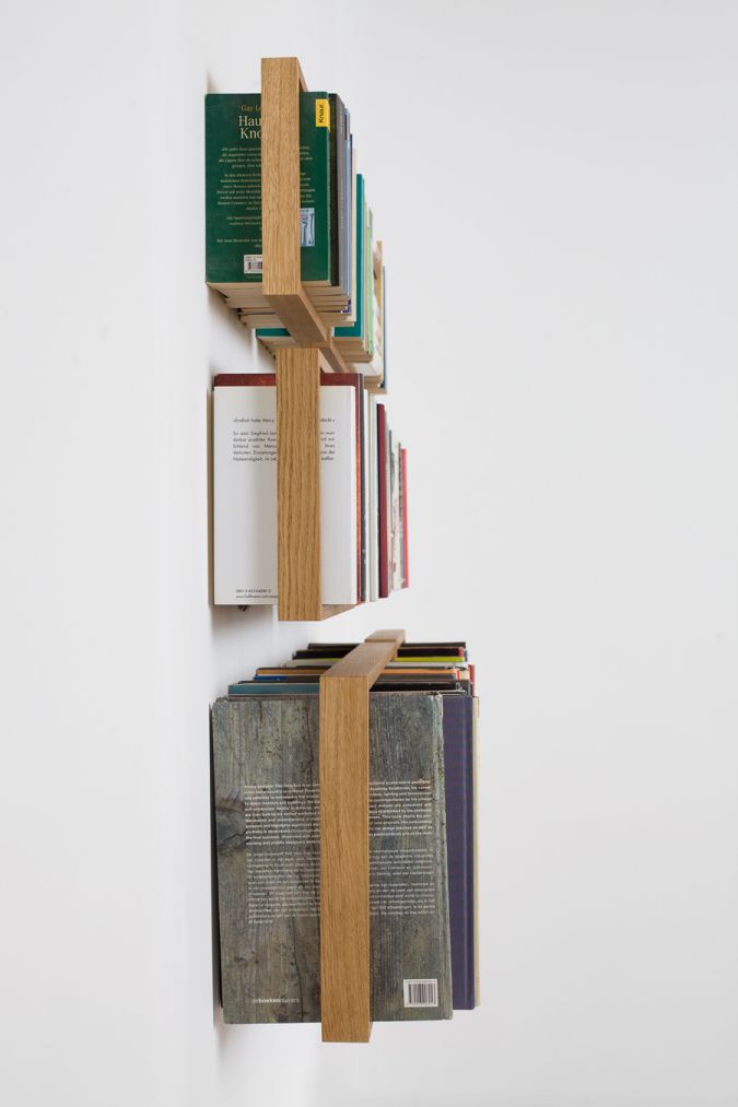 Wandmontiertes Regal b Eiche, minimalistisches Bücherregal aus hellem Holz, gefüllt mit Büchern, modernes Design für Wohnzimmer.