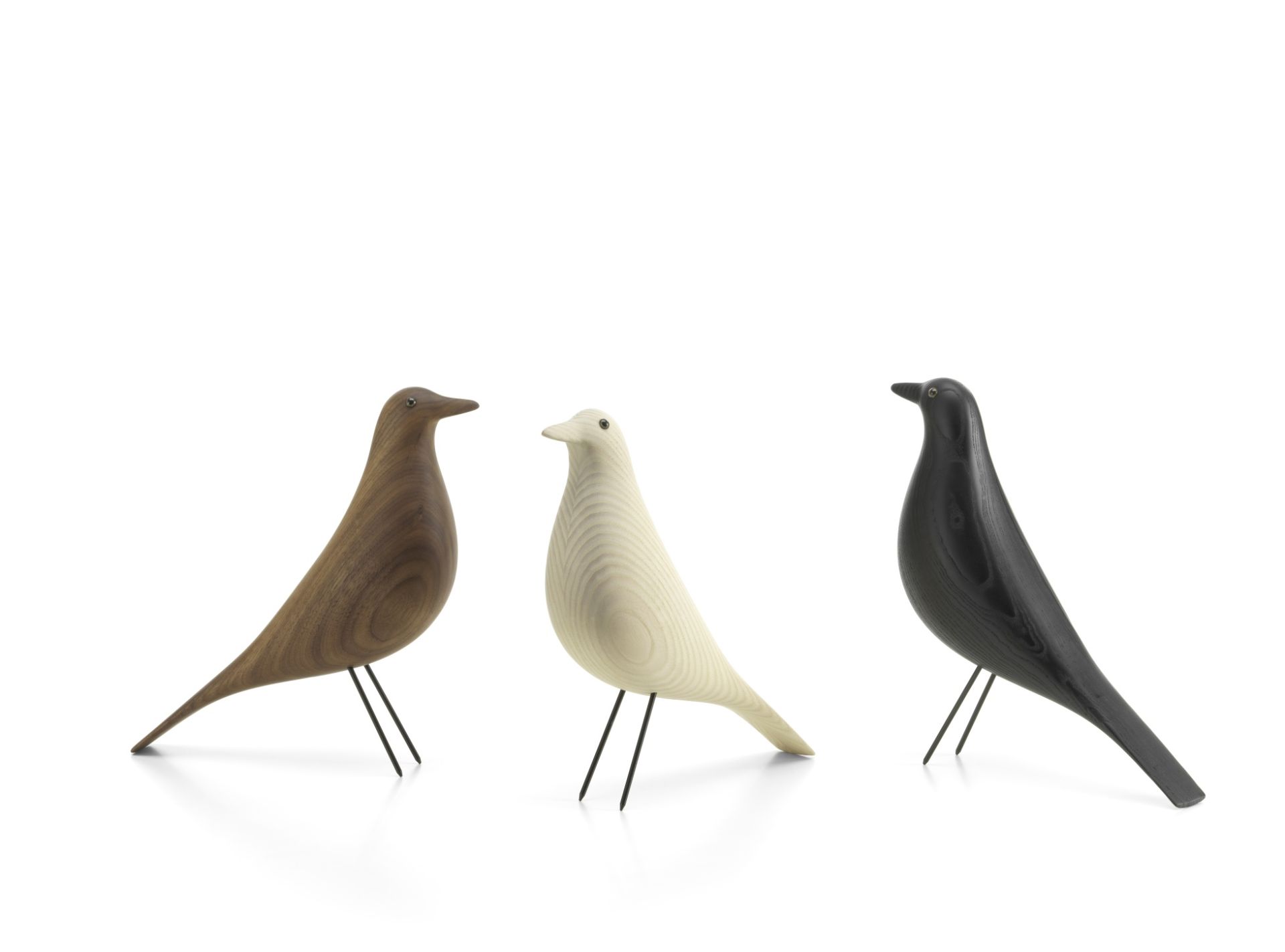 Drei Eames House Bird Holzfiguren von Vitra in Nussbaum, Weiß und Schwarz auf weißem Hintergrund.