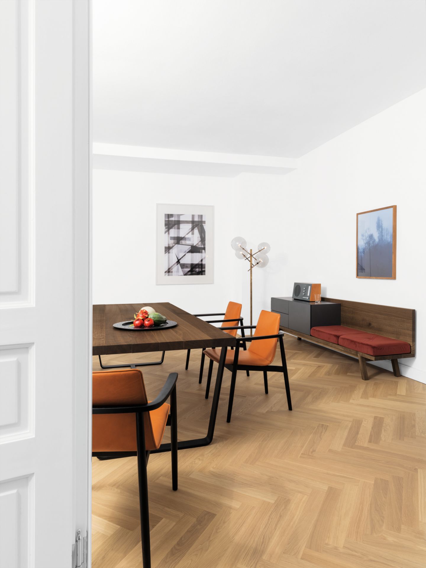 BB 11 Clamp Tisch Eiche geräuchert von Janua in modernem Esszimmer mit orangefarbenen Stühlen und Parkettboden.