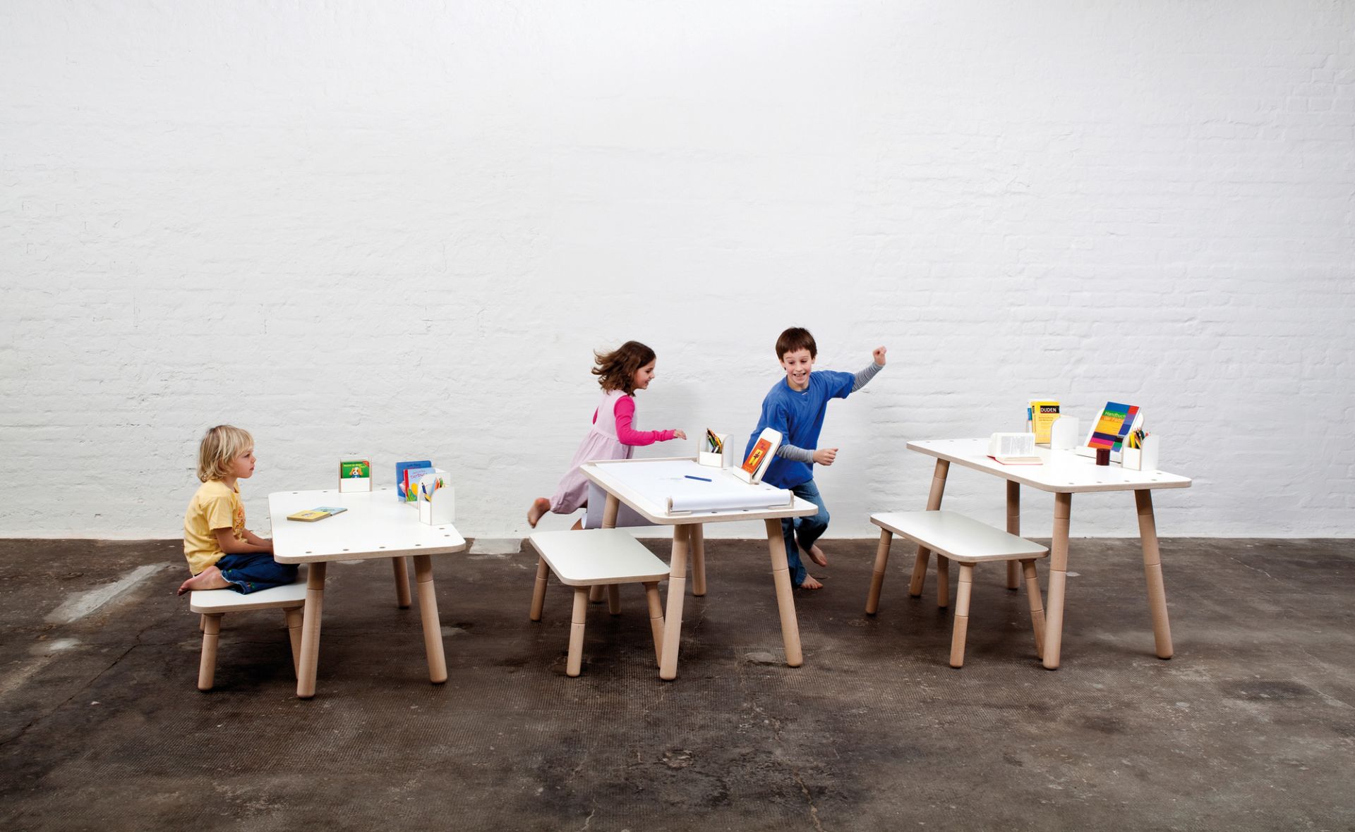 Growing Table Kindersitzgruppe: Kinder spielen an weißen Kindertischen und Stühlen der Marke Pure Position.