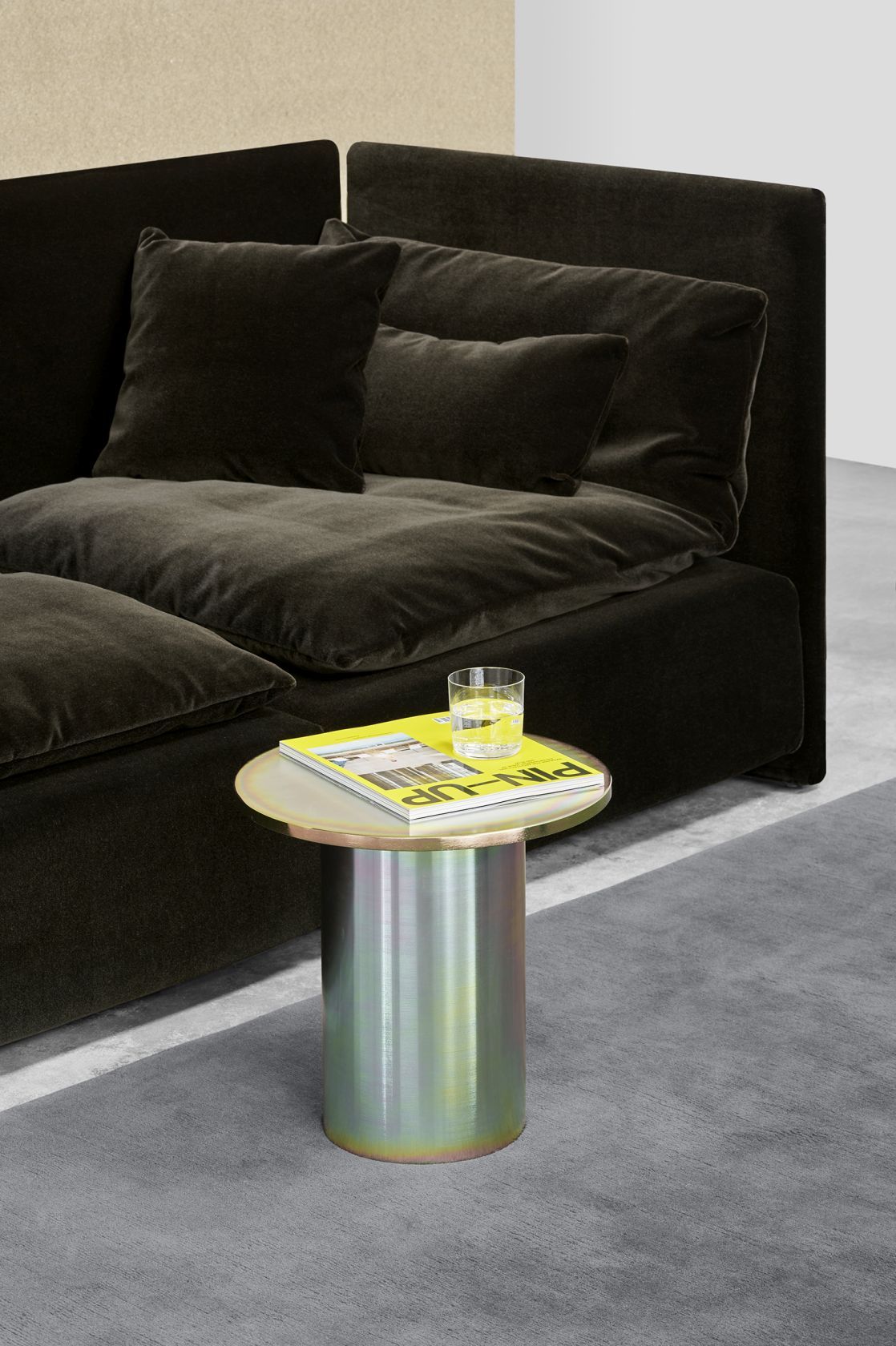 Enoki Beistelltisch von e15 neben Sofa: Runder Tisch mit Zeitschrift und Glas Wasser.