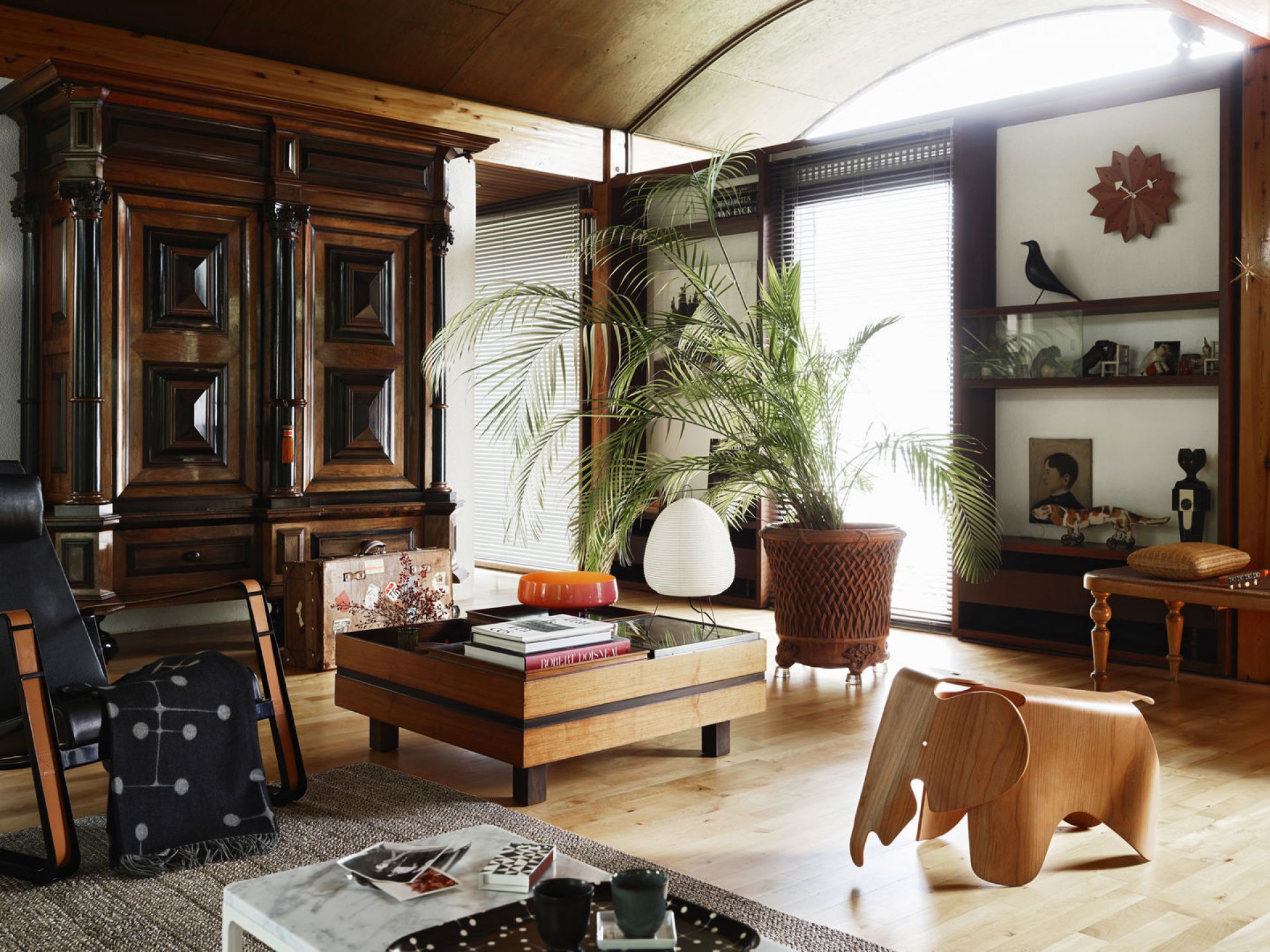 Innenaufnahme eines Wohnzimmers mit Vitra CitÉ Sessel, Holzschrank, Couchtisch, Zimmerpflanze und Dekoration.