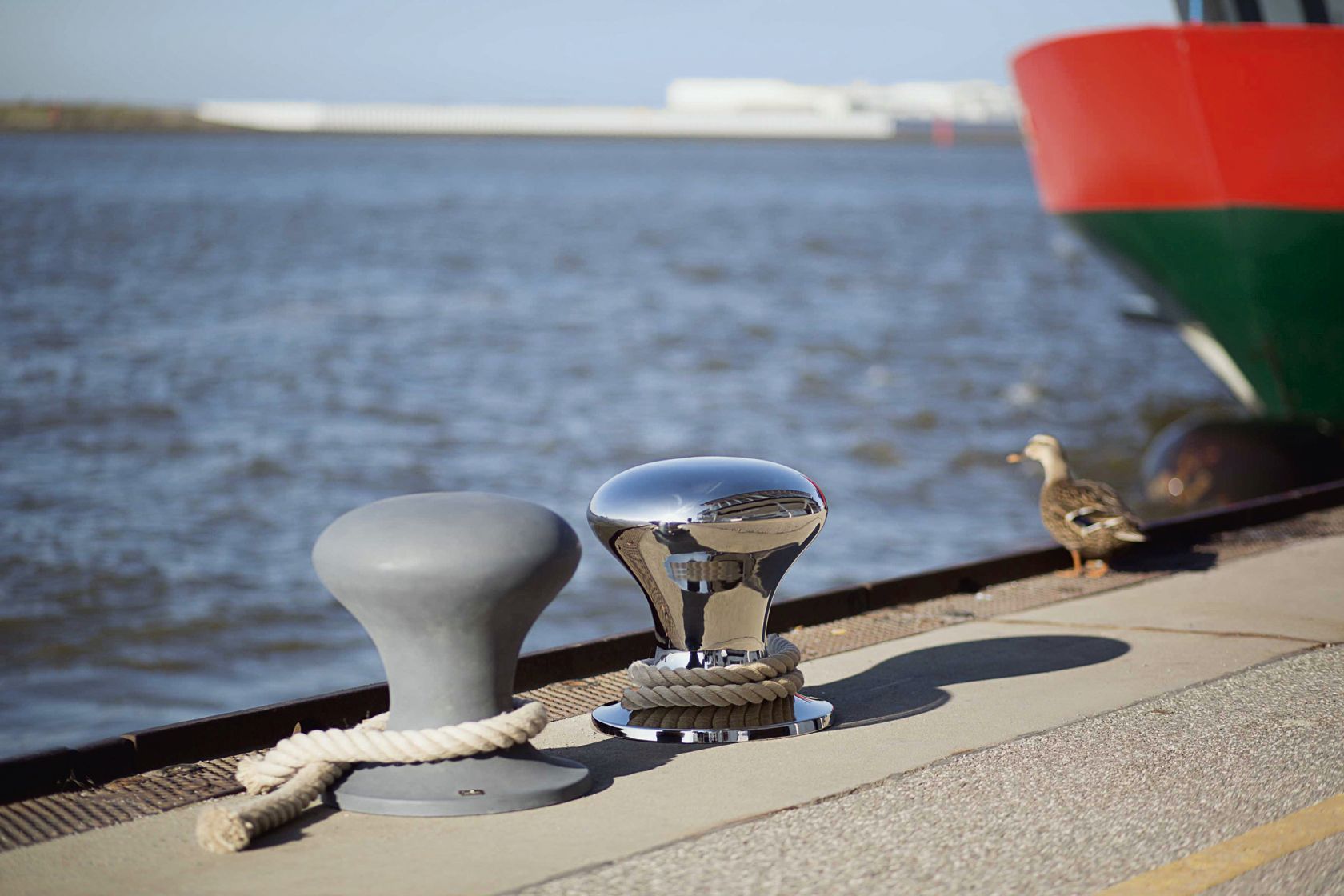 Hamburger Hocker poliert von Philippi neben einem grauen Hocker mit Seil am Hafen.