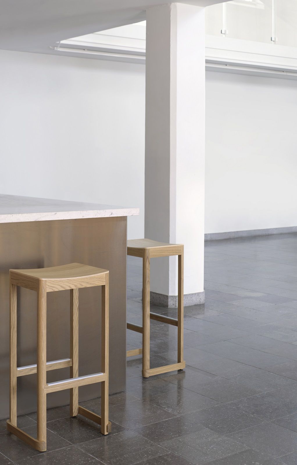 Zwei helle Holz-Barhocker, Atelier Bar Stool von Artek, an einer Kücheninsel in minimalistischem Interieur.