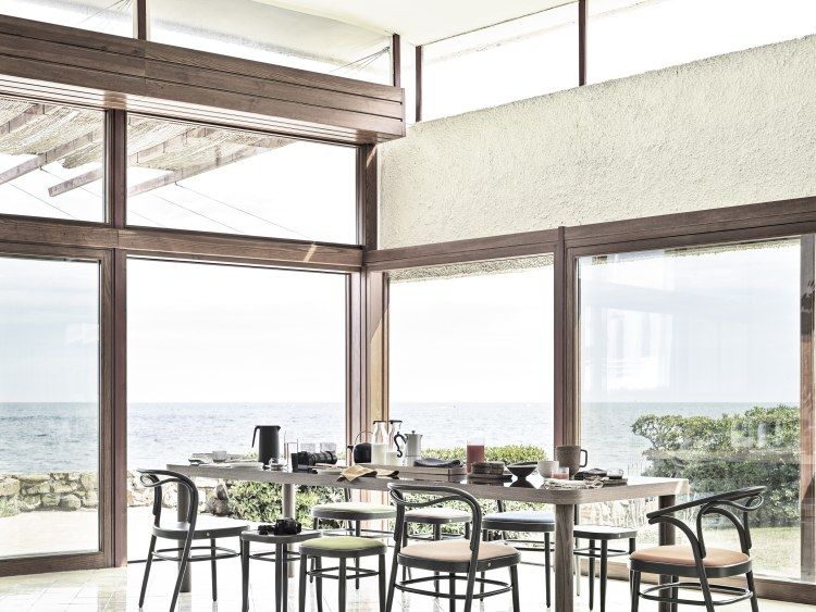 Esstisch mit Beaulieu Stühlen von Wiener GTV Design vor Panoramafenster mit Meerblick.