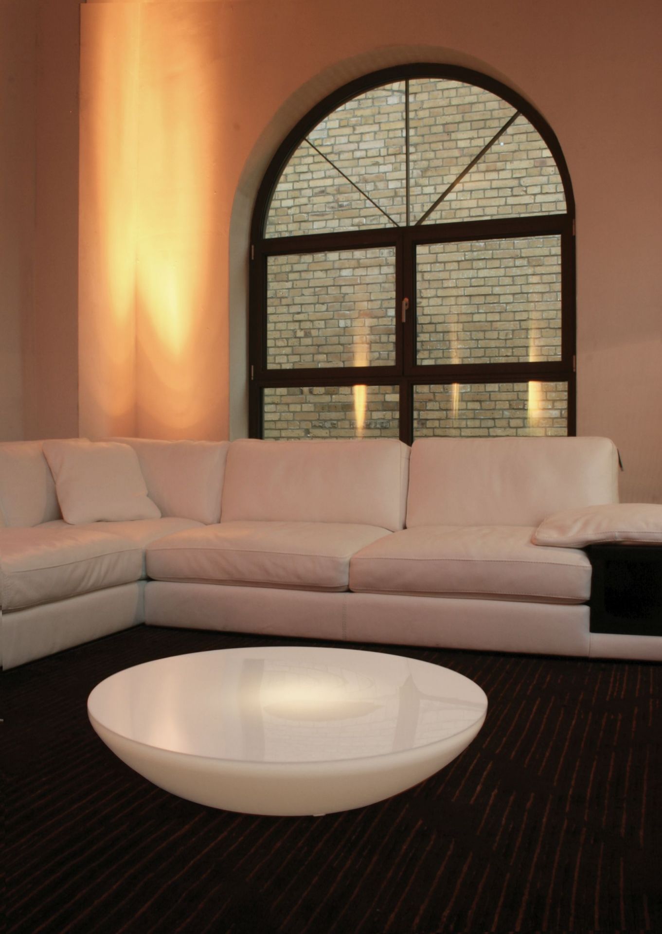 Helle Lounge Couch mit Moree Couchtisch in modernem Wohnzimmer mit großem Fenster.