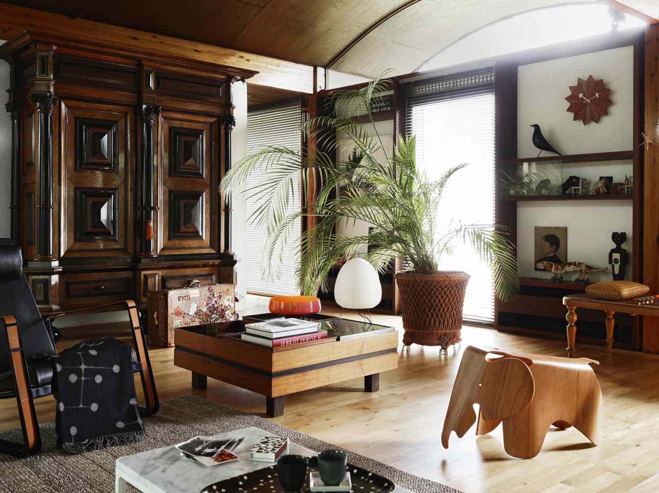 Wohnzimmer Interieur mit Holzmöbeln, großem Schrank, Couchtisch, Zimmerpflanze und hölzernem Elefanten Hocker.