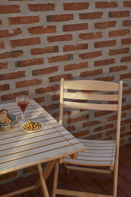 Selandia Stuhl von Skagerak by Fritz Hansen aus Holz mit Tisch und Snacks im Freien.