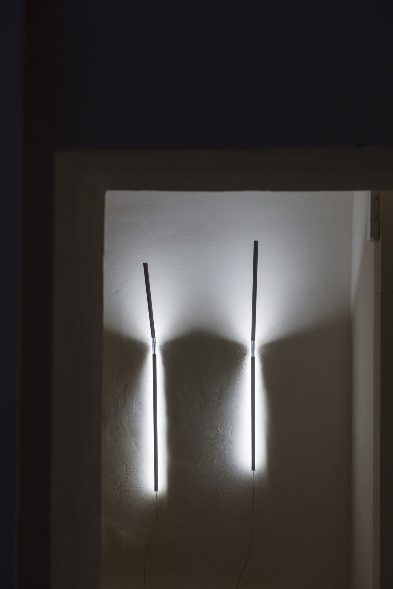 Zwei minimalistische Measure Light Wandleuchten von Ingo Maurer an einer weißen Wand, indirekte Beleuchtung.