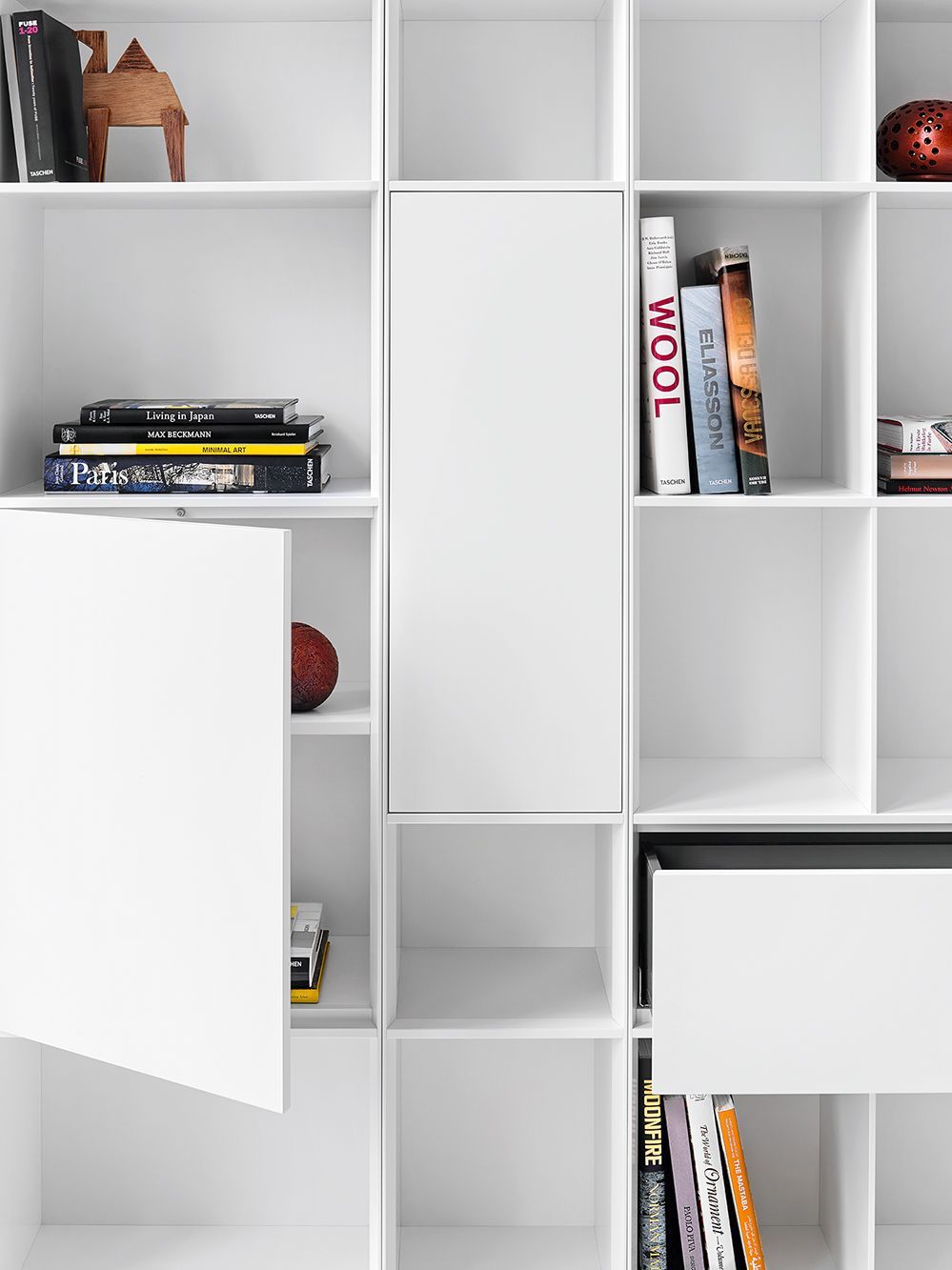Weißes Nex Pur Regal mit Tür, Fachboden und dekorativen Büchern. Modernes Regalsystem für Wohnzimmer und Büro.
