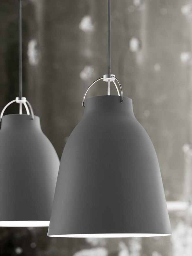Nahaufnahme von zwei grauen Caravaggio Pendelleuchten von Fritz Hansen mit sanftem Lichtschein.