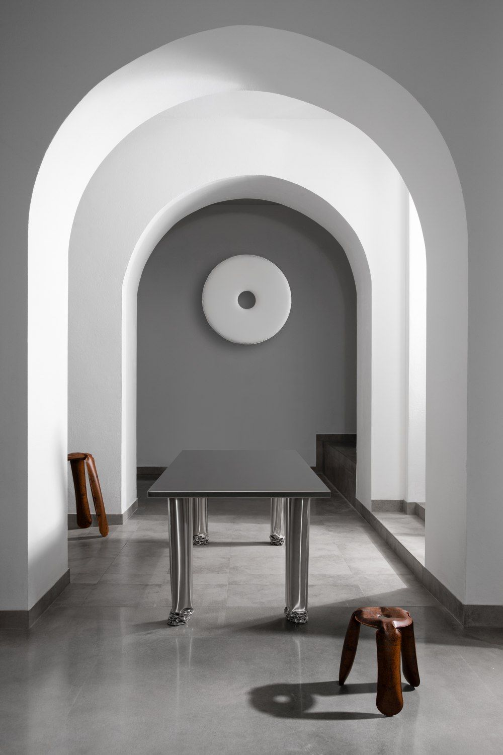 Crash Table Esstisch von Zieta im minimalistischen Raum mit Bögen und Holzstühlen, modernes Design.