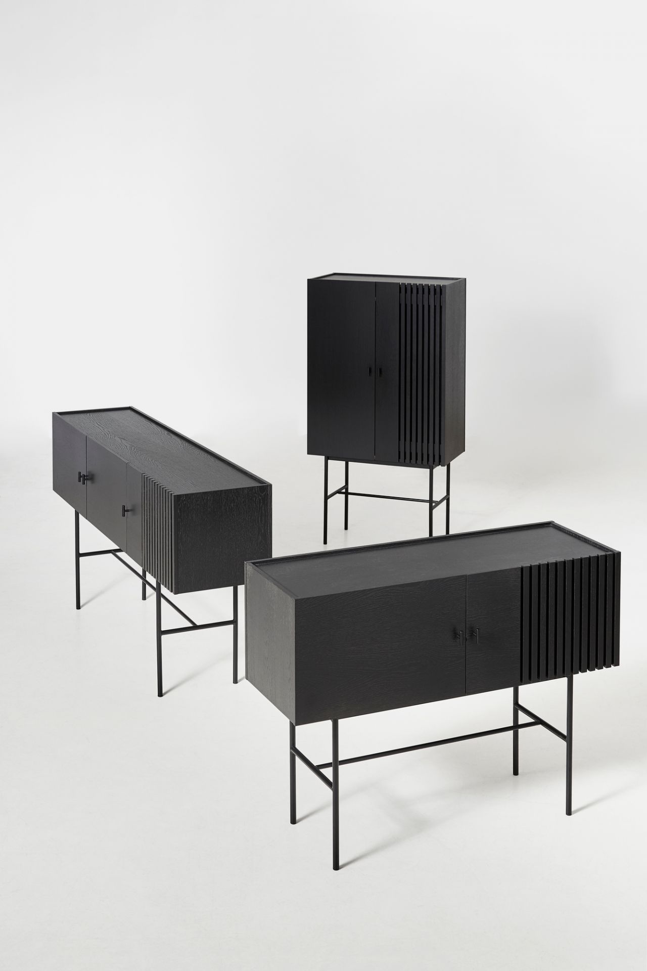 Schwarze Array Highboards von Woud aus Eiche mit Lamellenfront und filigranem Metallgestell.