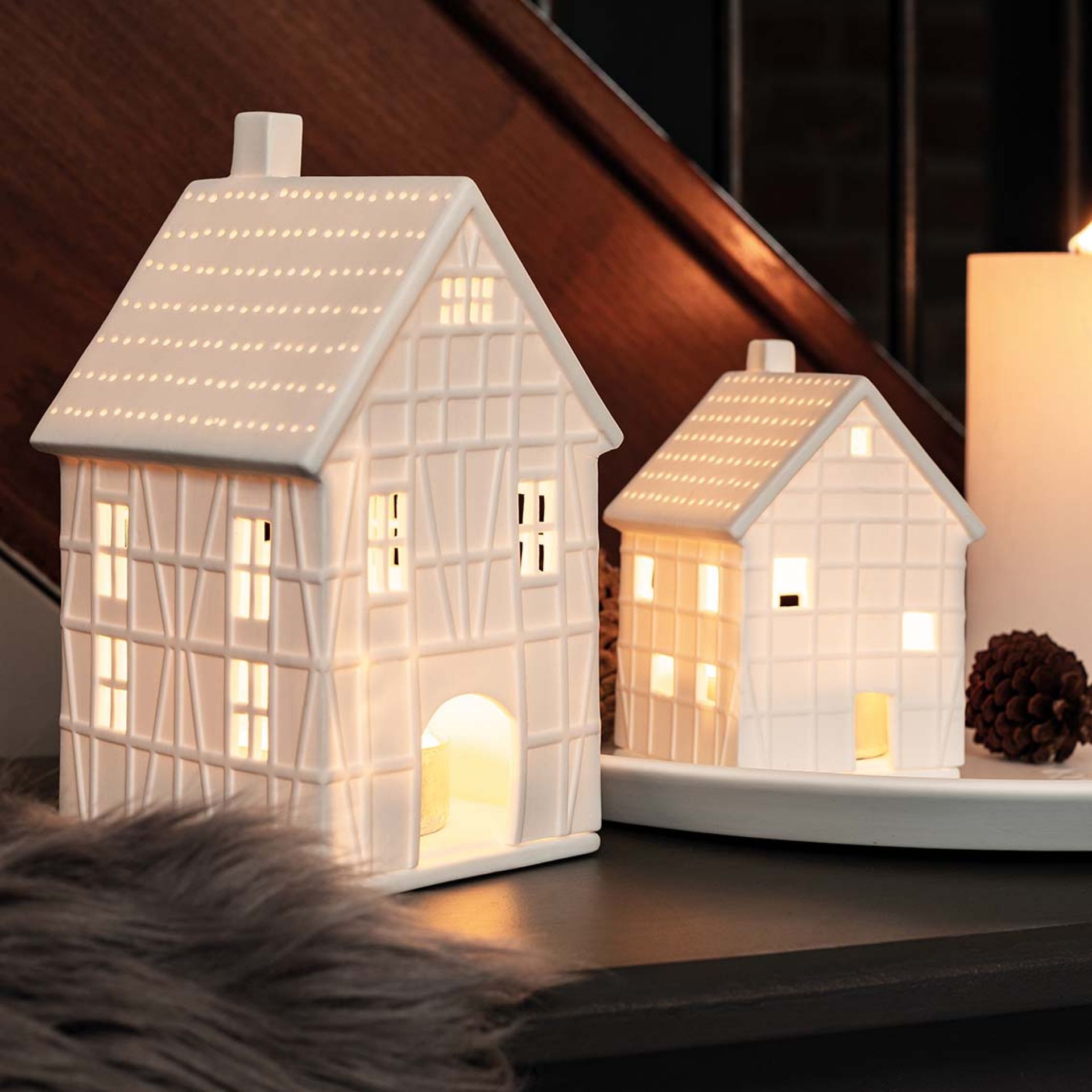 Zwei beleuchtete, weiße Keramik-Fachwerkhäuser von Räder, stimmungsvolle Dekoration für Weihnachten und Winter.
