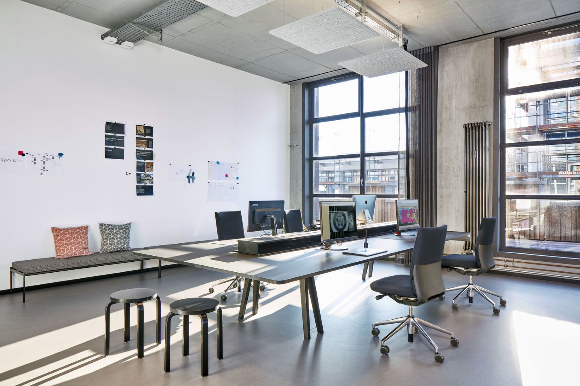 Helles Büro mit Vitra ID Soft Bürodrehstühlen, großem Tisch, Hockern und Bänken für moderne Arbeitsplätze.