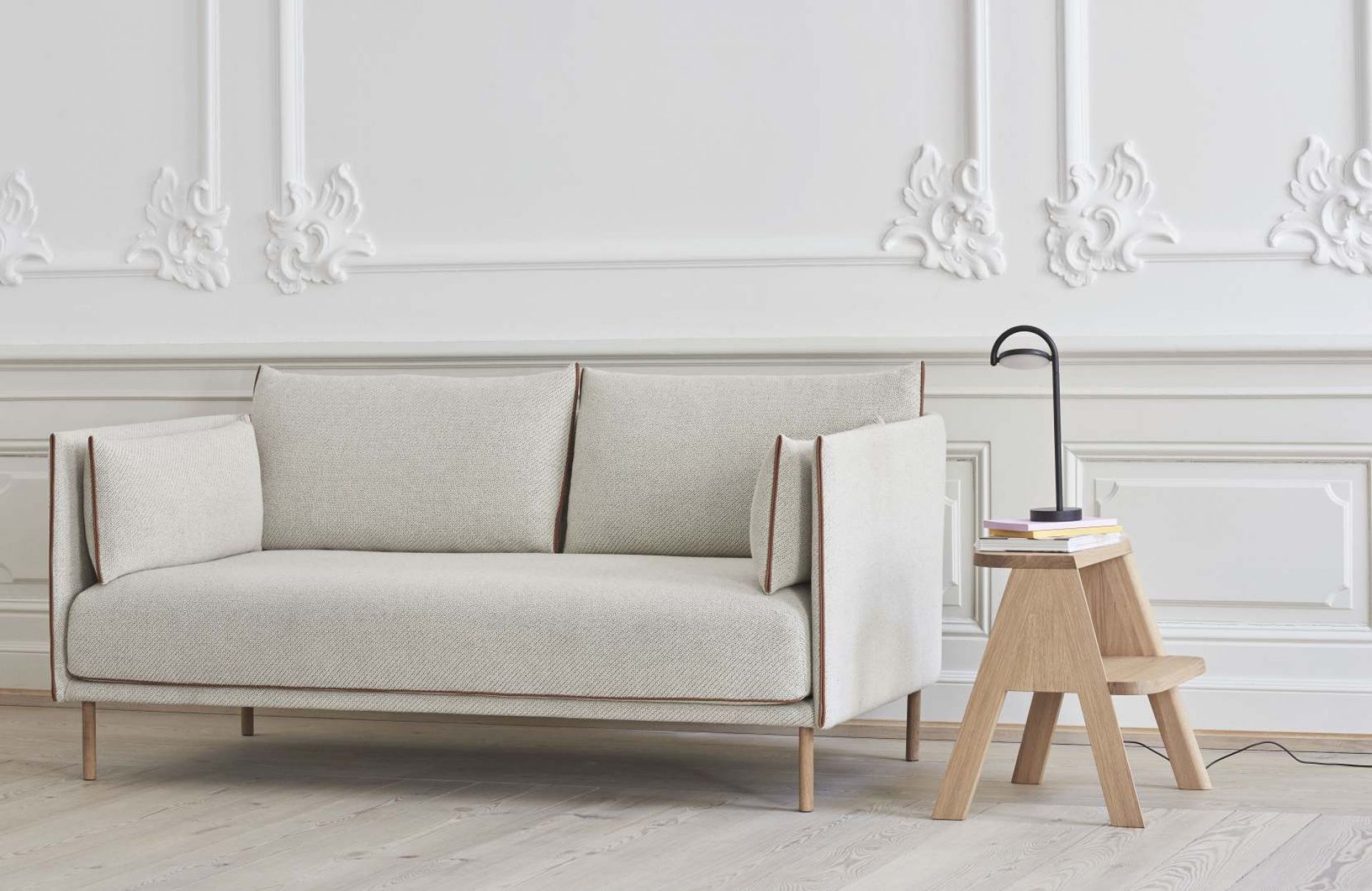 Heller Butler Hocker von Hay aus Holz mit Lampe neben einem beigen Sofa.