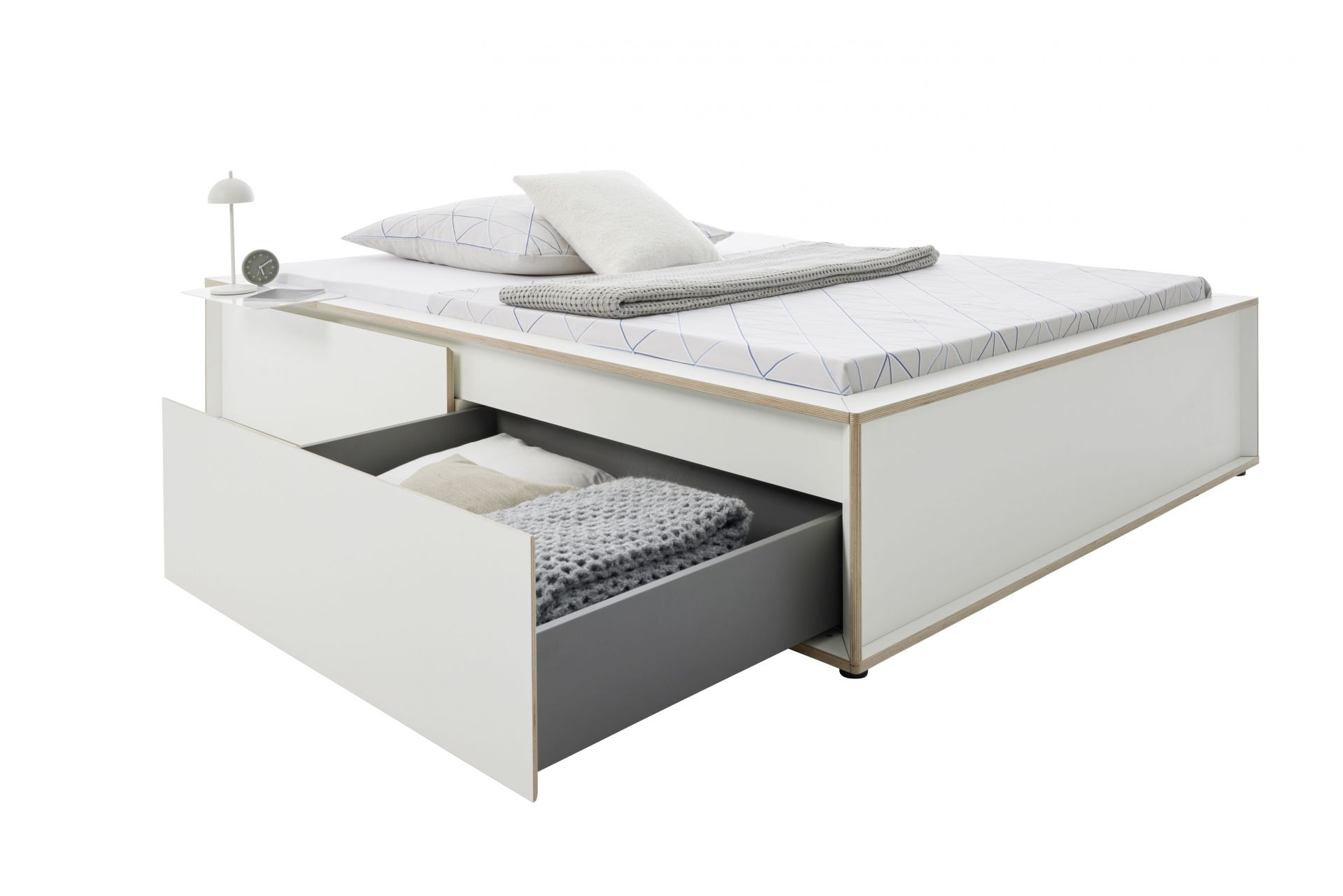 Spaze Bett von Müller Möbelwerkstätten in Weiß mit Schublade, Nachttisch, Lampe und Textilien.