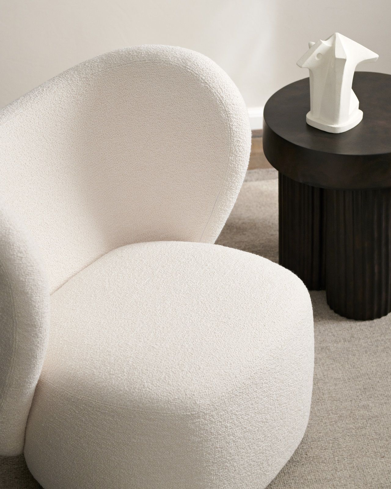 Gear Tall Side Table von Norr11 neben einem Sessel: Runder Beistelltisch aus dunklem Holz.