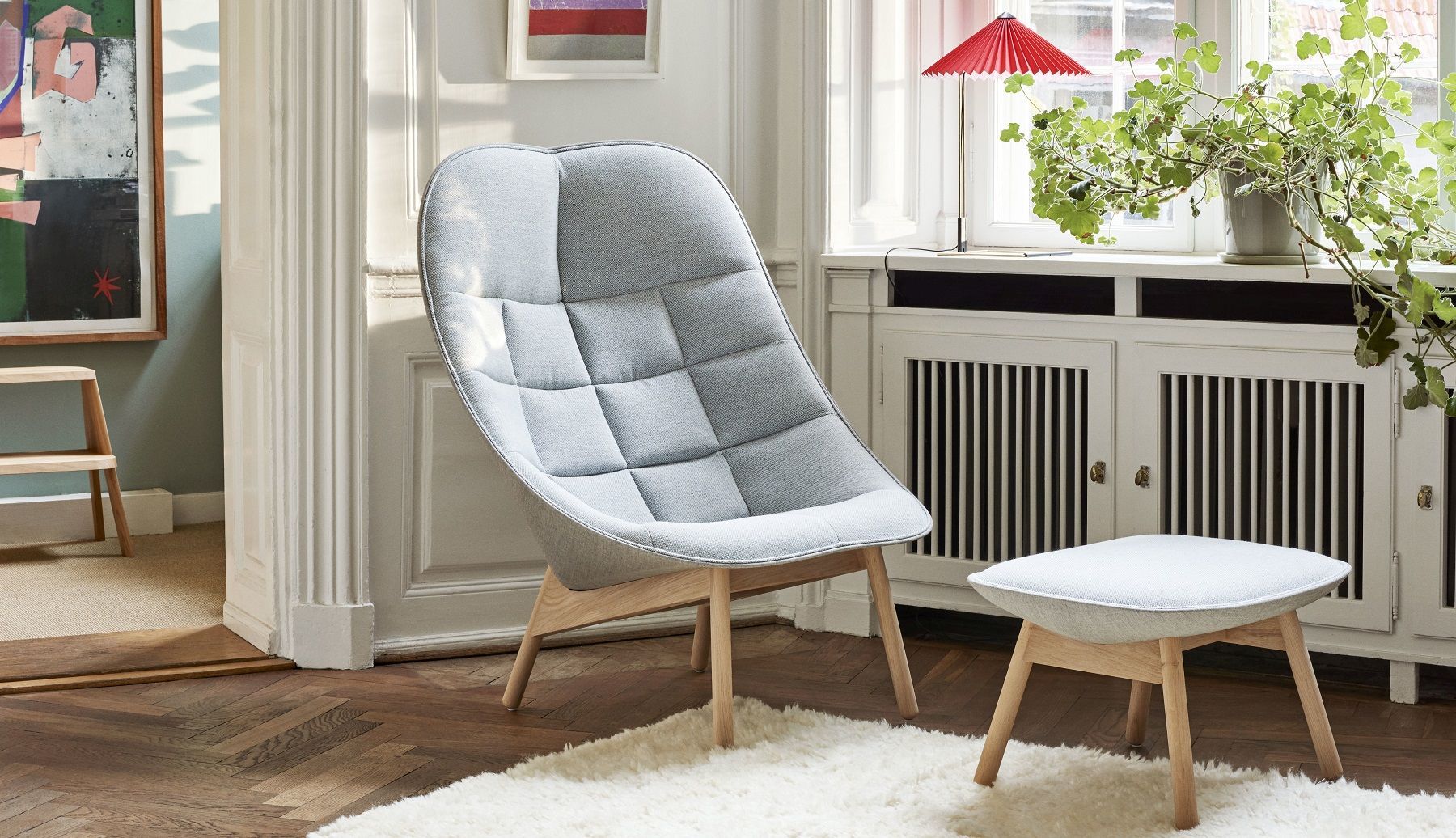 Uchiwa Ottoman Hocker von Hay, hellgrauer Polsterhocker mit Holzbeinen im modernen Wohnzimmer.