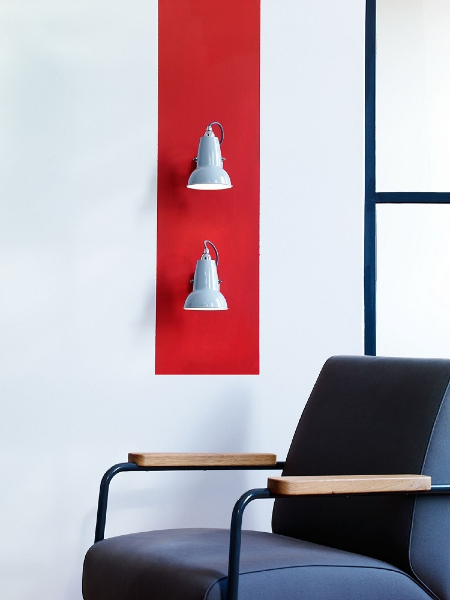 Zwei graue Anglepoise 1227 Mini Wandleuchten an roter Wand über einem Sessel.