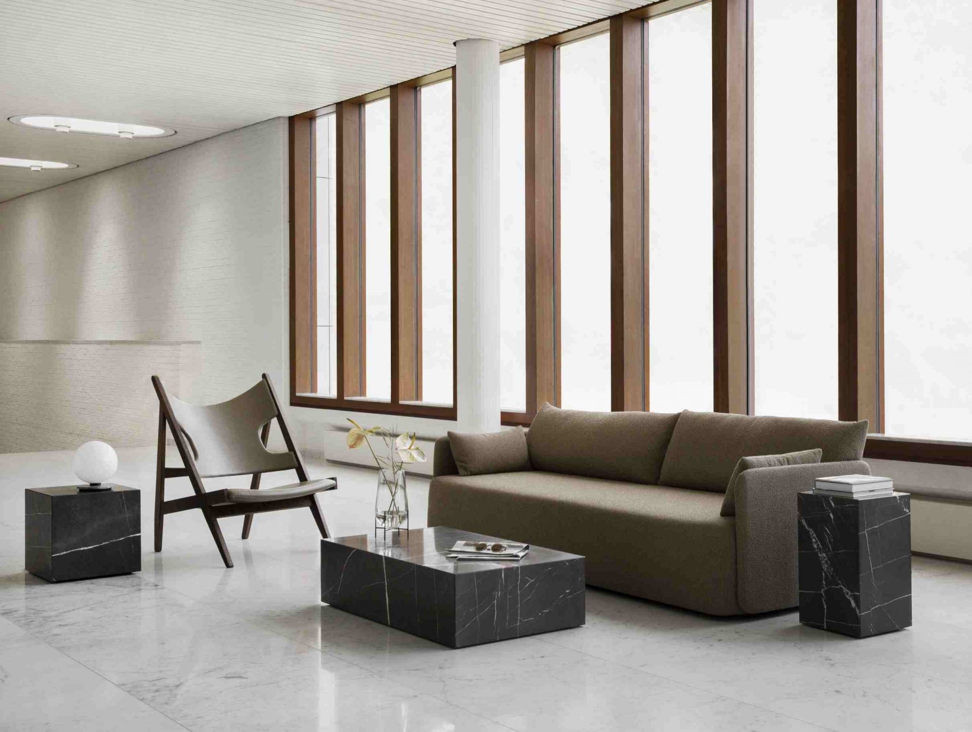 Audo Plinth Cubic Beistelltisch aus Marmor in modernem Wohnzimmer mit Sofa und Sessel.