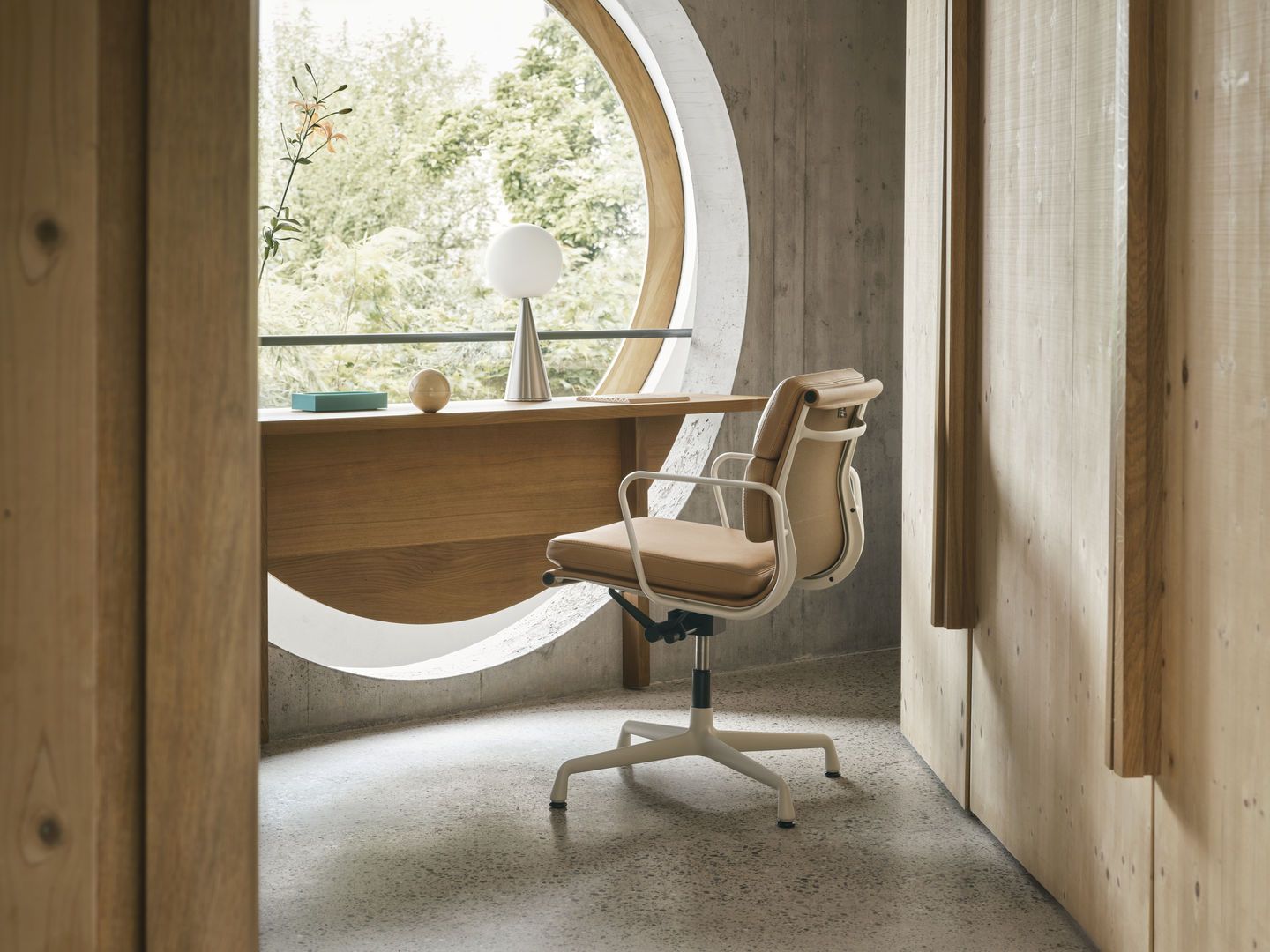 Vitra EA 231 Soft Pad Chair in Beige vor einem runden Fenster und Holzwand.
