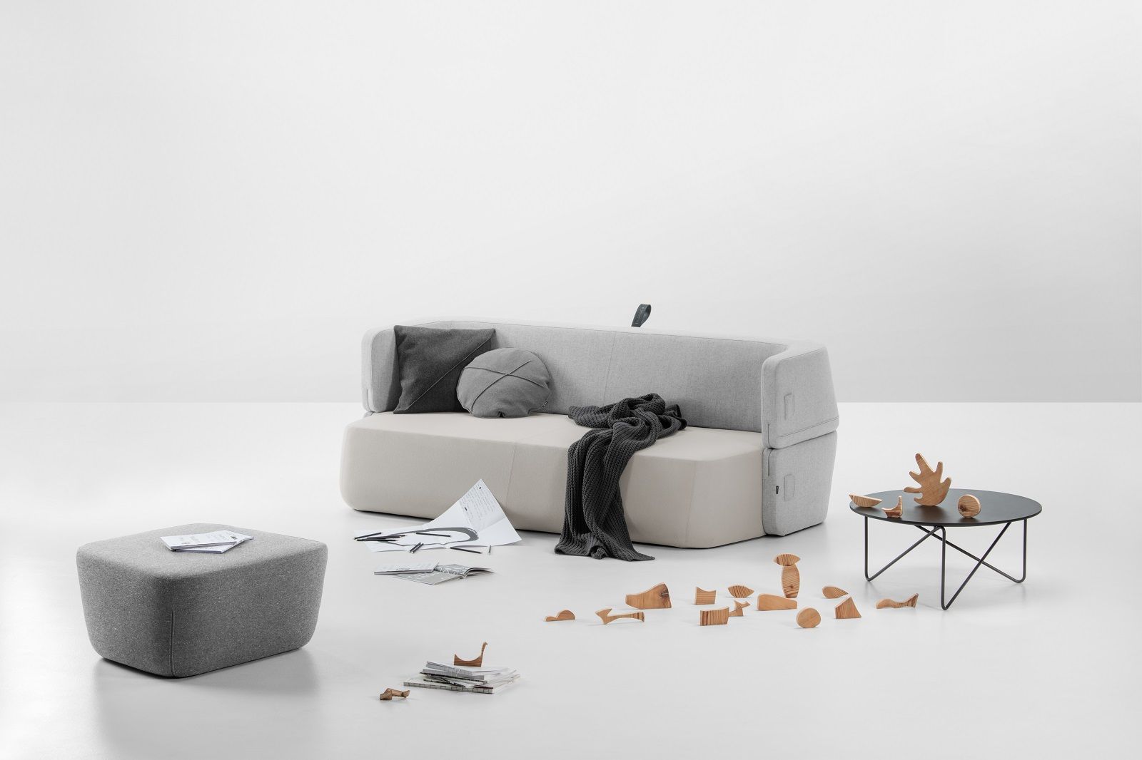 Revolve Schlafsofa von Prostoria in hellem Grau mit Kissen und Decke, minimalistisches Design für Wohnzimmer.