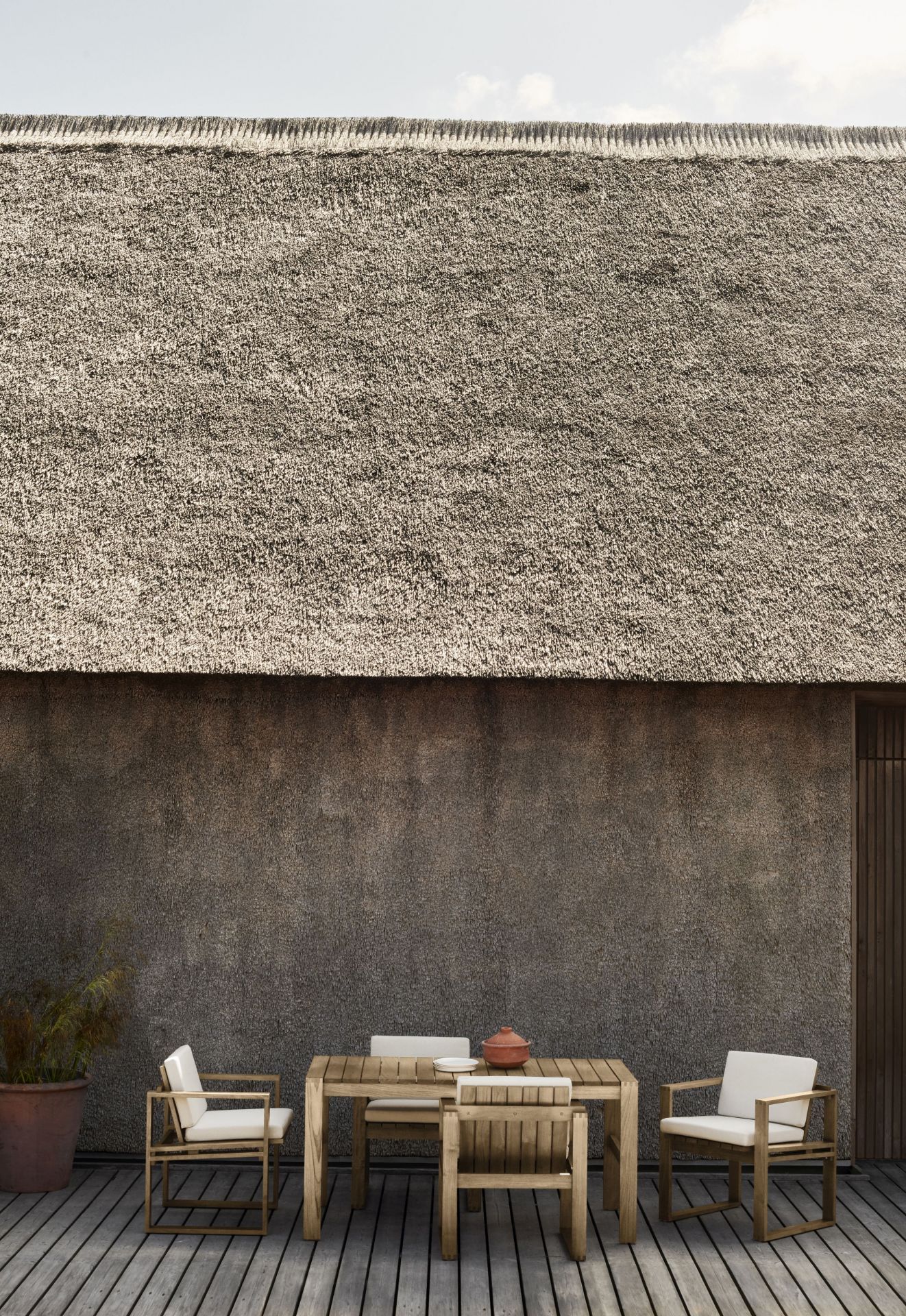 Bodil Kjaer Outdoorstuhl von Carl Hansen & Søn mit Tisch und Stühlen auf Holzterrasse.