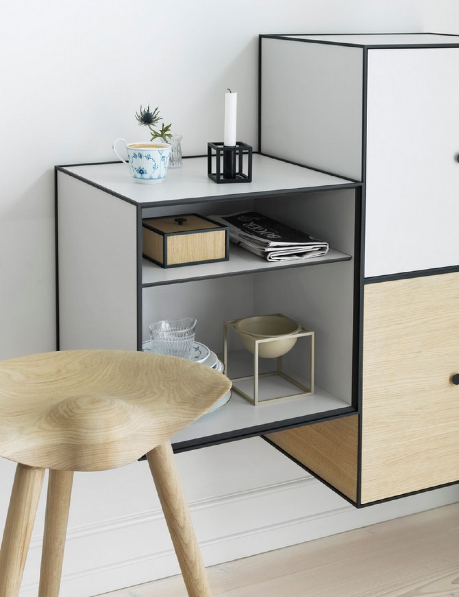 Audo ML42 Thekenhocker aus hellem Holz vor modernem, weißen Regalsystem mit Deko-Elementen.