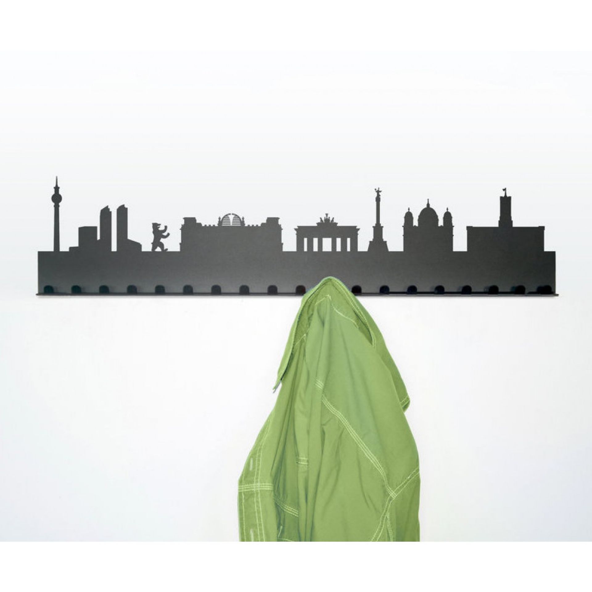 Schwarze Skyline Garderobe Berlin mit Sehenswürdigkeiten und grüner Jacke an weißer Wand.