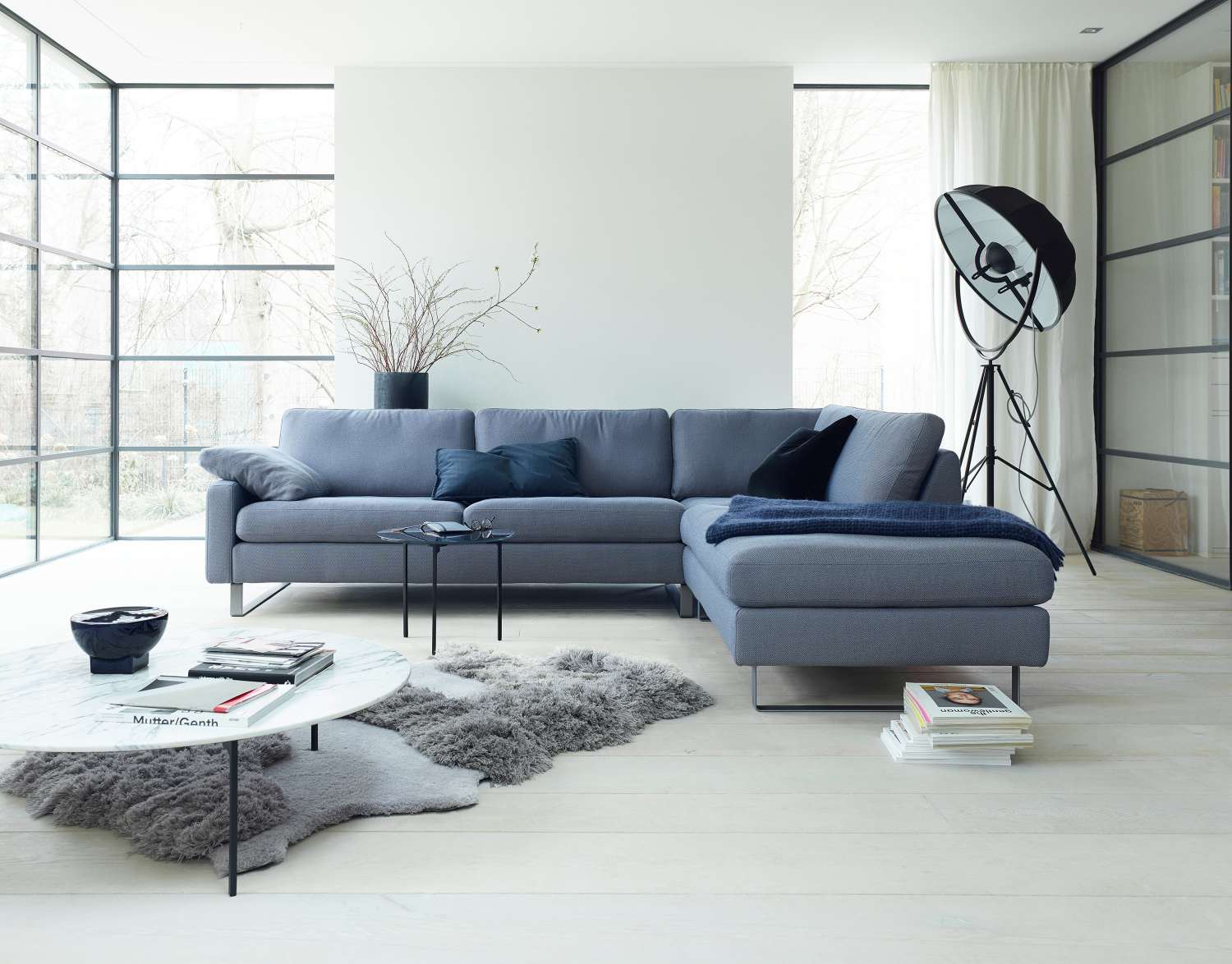 Graues Conseta Sofa von Cor mit Ottomane, Kissen und Beistelltischen in modernem Wohnzimmer.