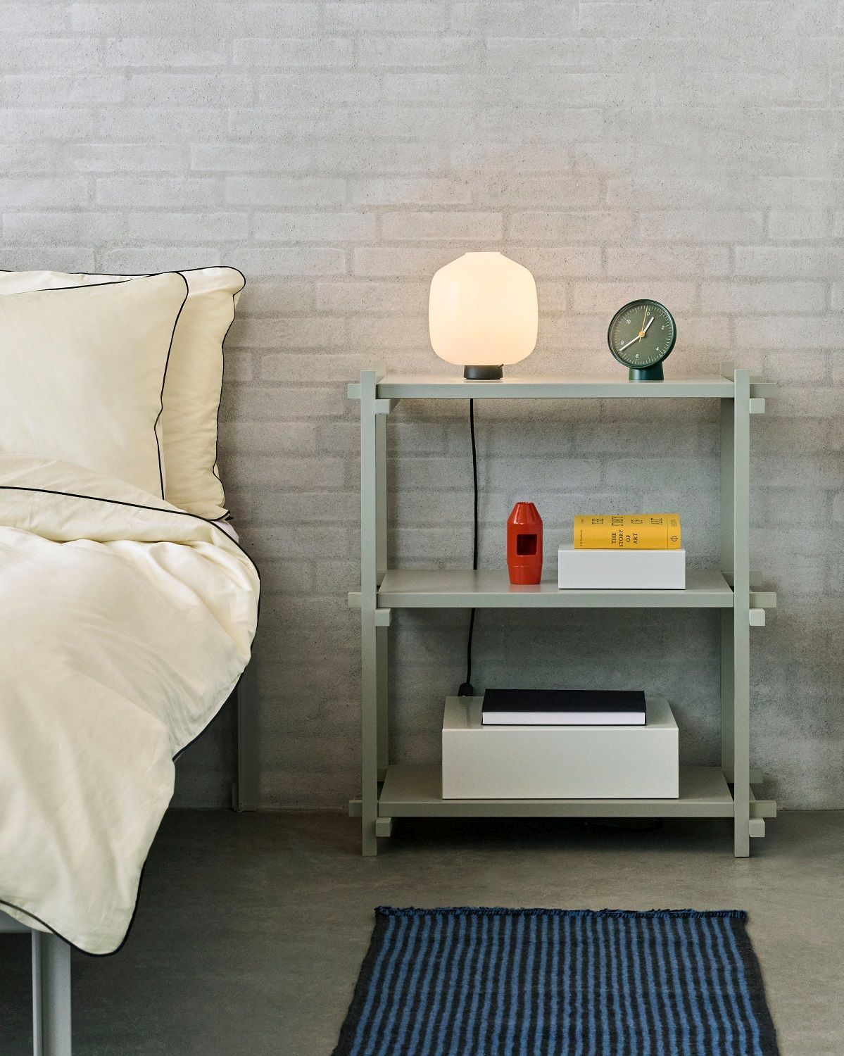 Helles Schlafzimmer mit Hay Woody Column Low Regal, Lampe, Uhr und Teppich.