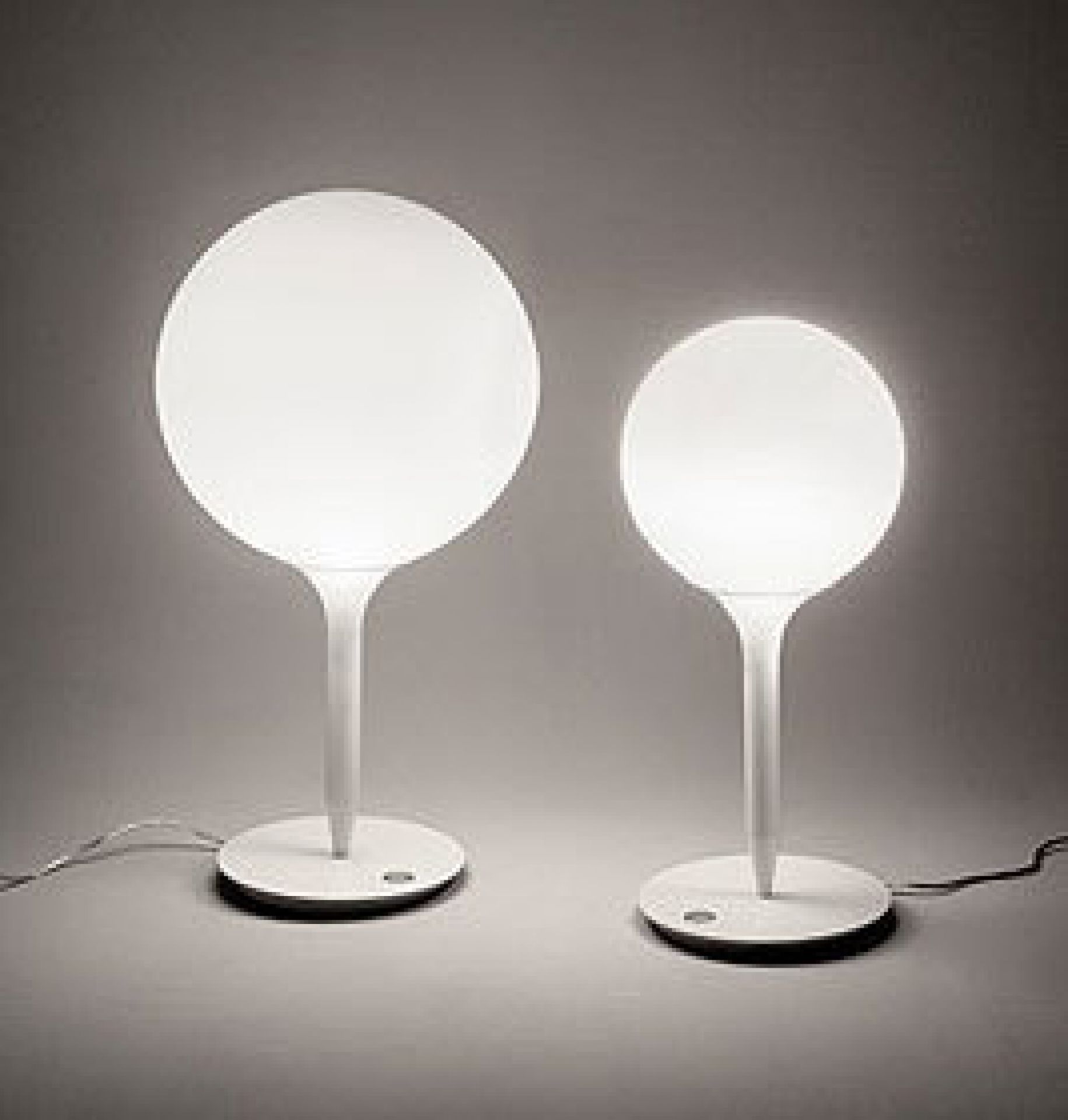 Zwei weiße Castore Tischleuchten von Artemide mit runden Lampenschirmen spenden warmes Licht.