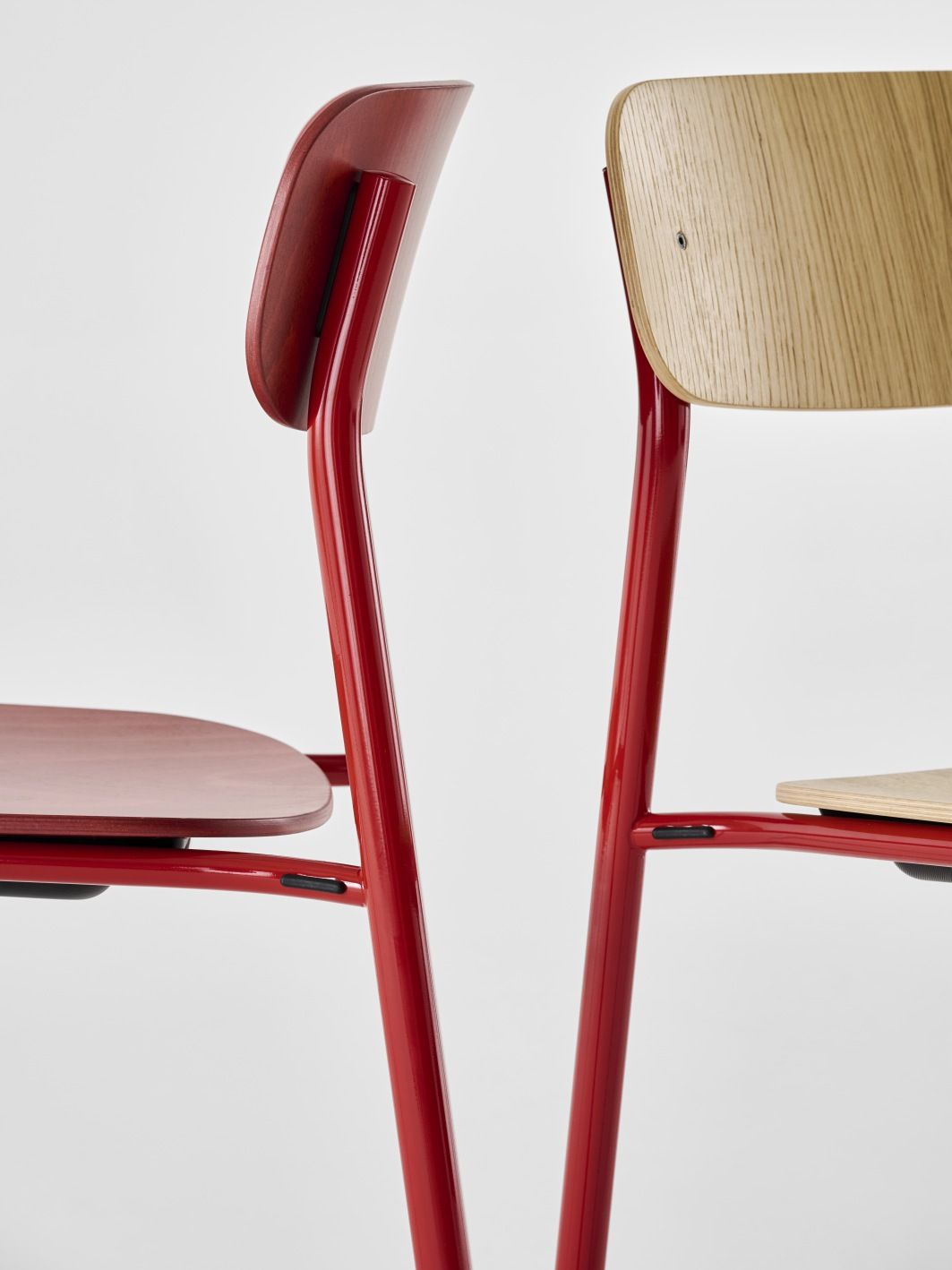Detailaufnahme von zwei S 243 Stahlrohrstühlen von Thonet, einer rot gebeizt, einer naturfarben, minimalistisches Design.