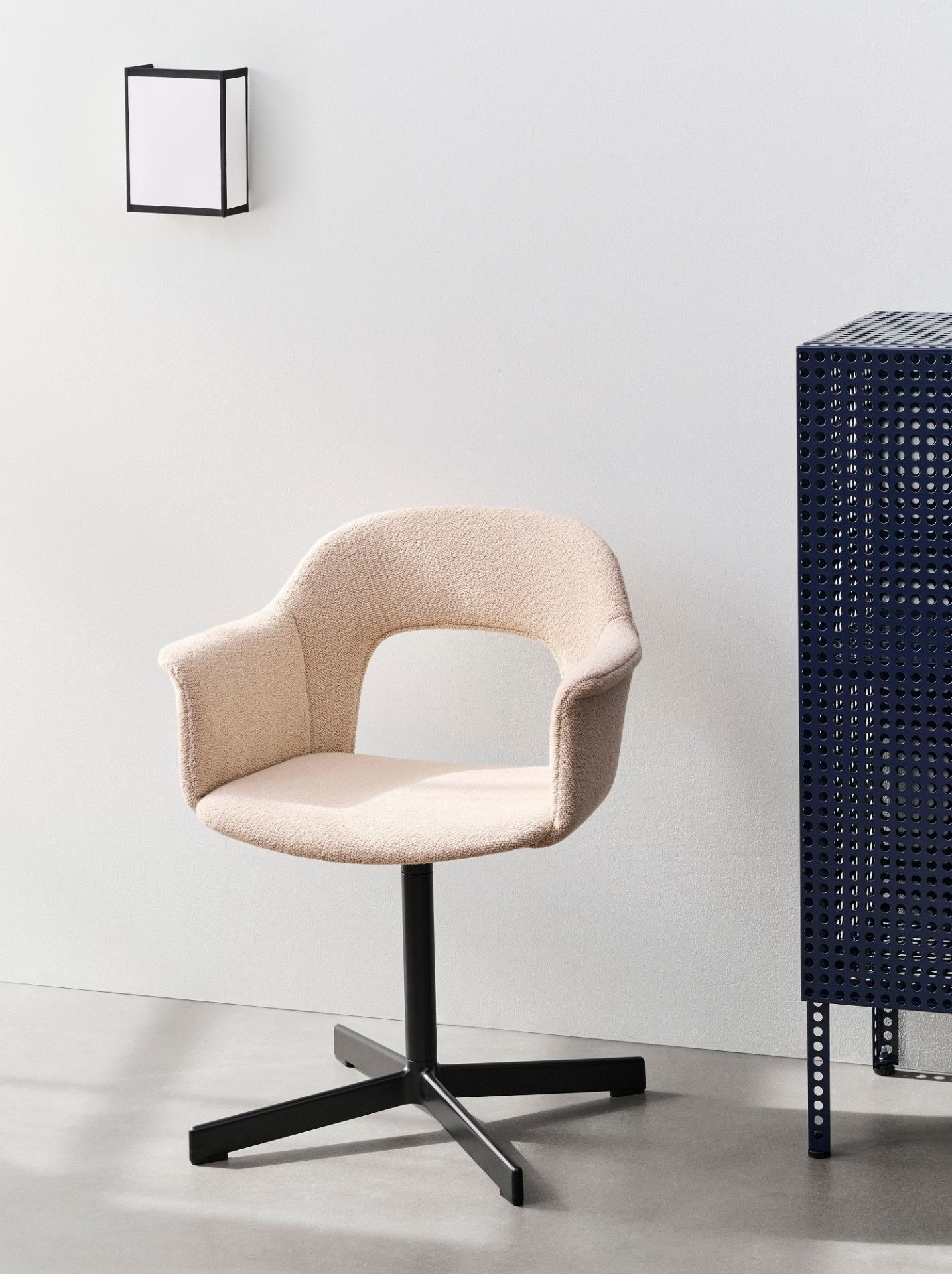 Nahaufnahme der Hay Ava Square Wandleuchte, eines beigen Sessels und eines blauen perforierten Schranks.