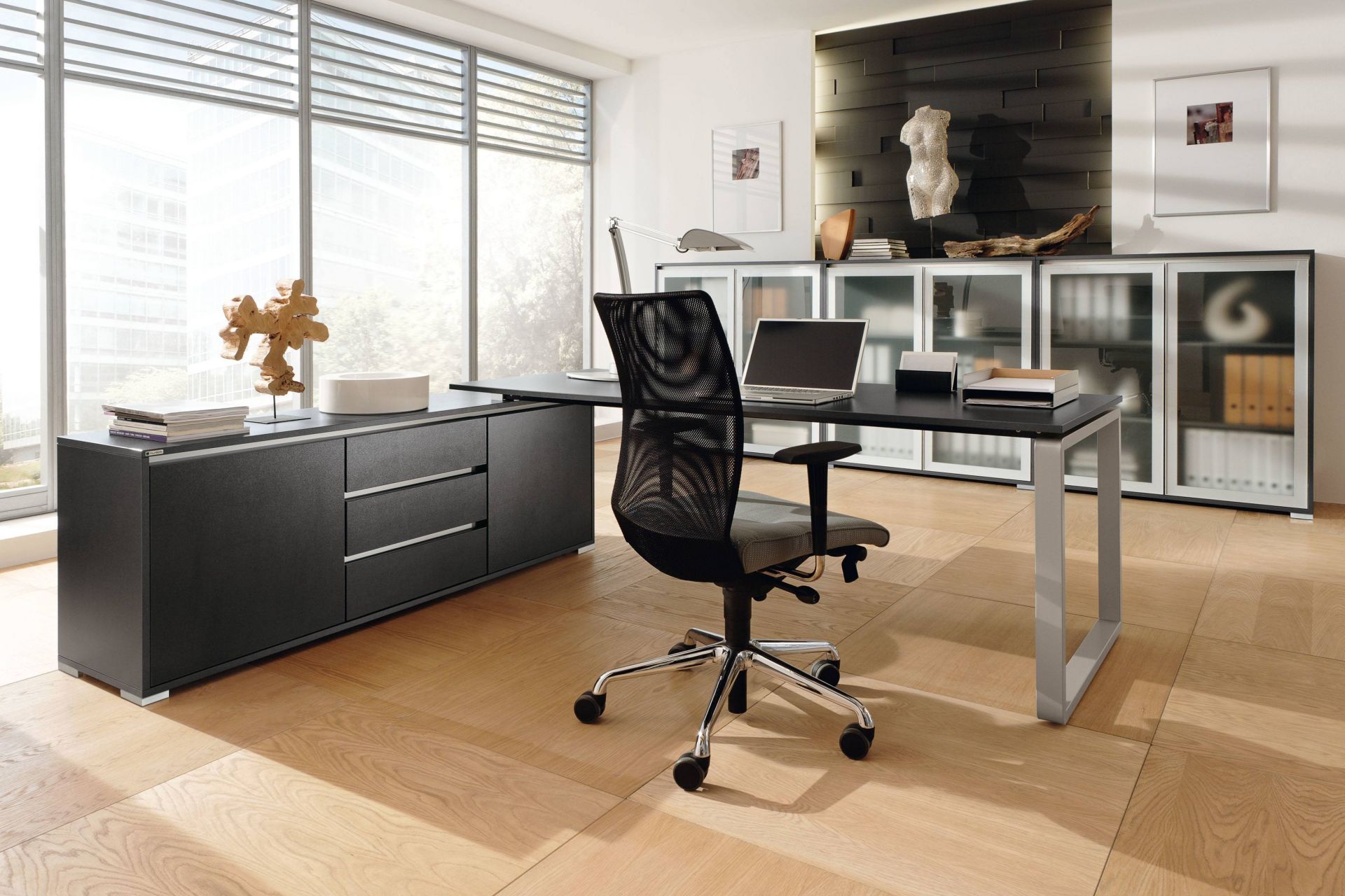Büro mit Palmberg Schreibtisch, schwarzem Bürostuhl und Sideboard vor Fenster. Modernes Bürodesign.