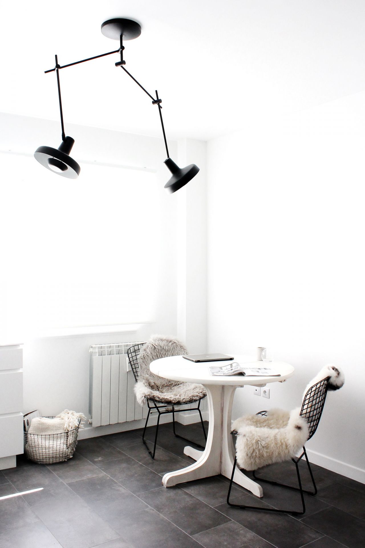 Esszimmer mit Arigato Deckenleuchte, schwarze Pendelleuchte über weißem Tisch und Stühlen mit Fell.