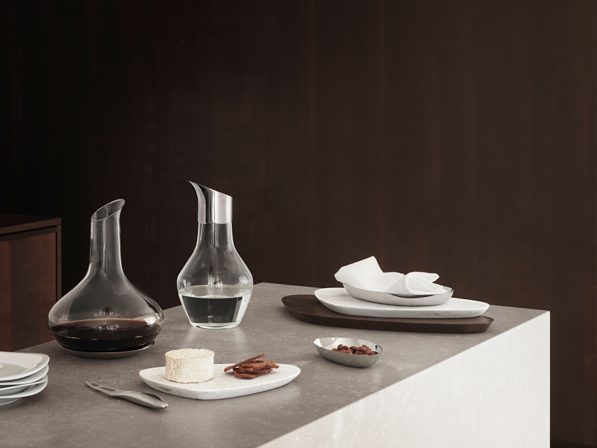 Sky Weinkaraffe von Georg Jensen mit Untersetzer, gefüllt mit Rotwein und Wasser, auf Tisch.