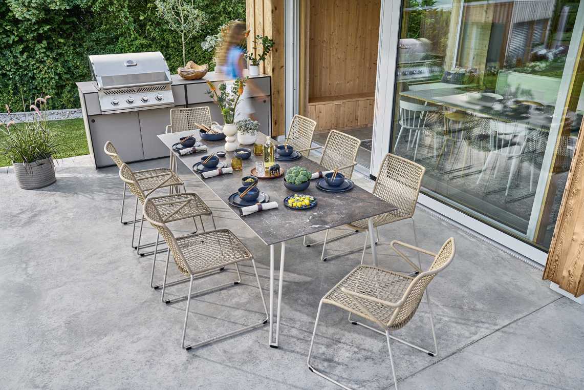 Slope Tisch von Weishäupl: Moderner Esstisch für den Außenbereich mit Stühlen und Grill.