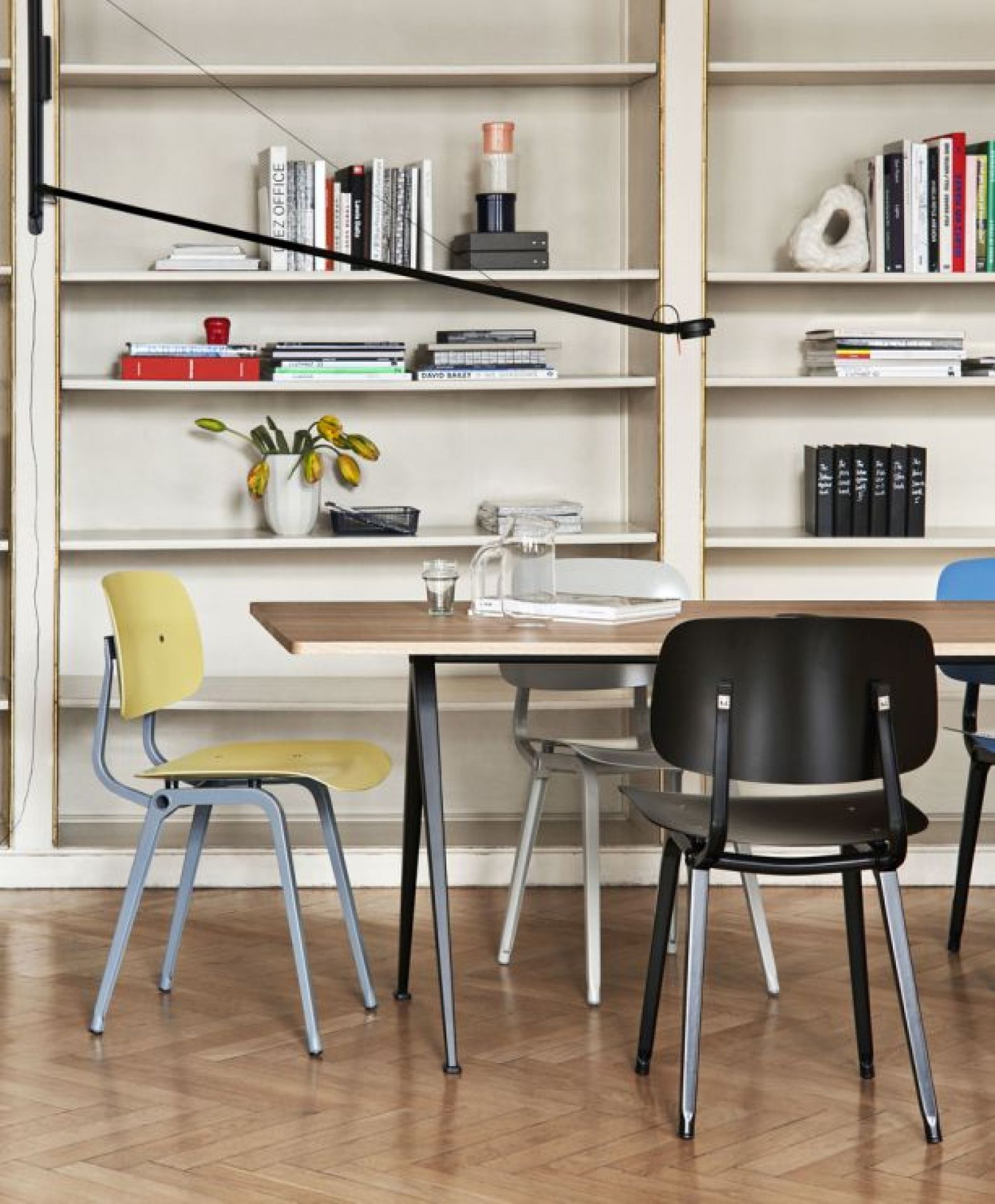 Gelber Revolt Chair Stuhl von Hay am Esstisch vor Bücherregal, modernes skandinavisches Design.