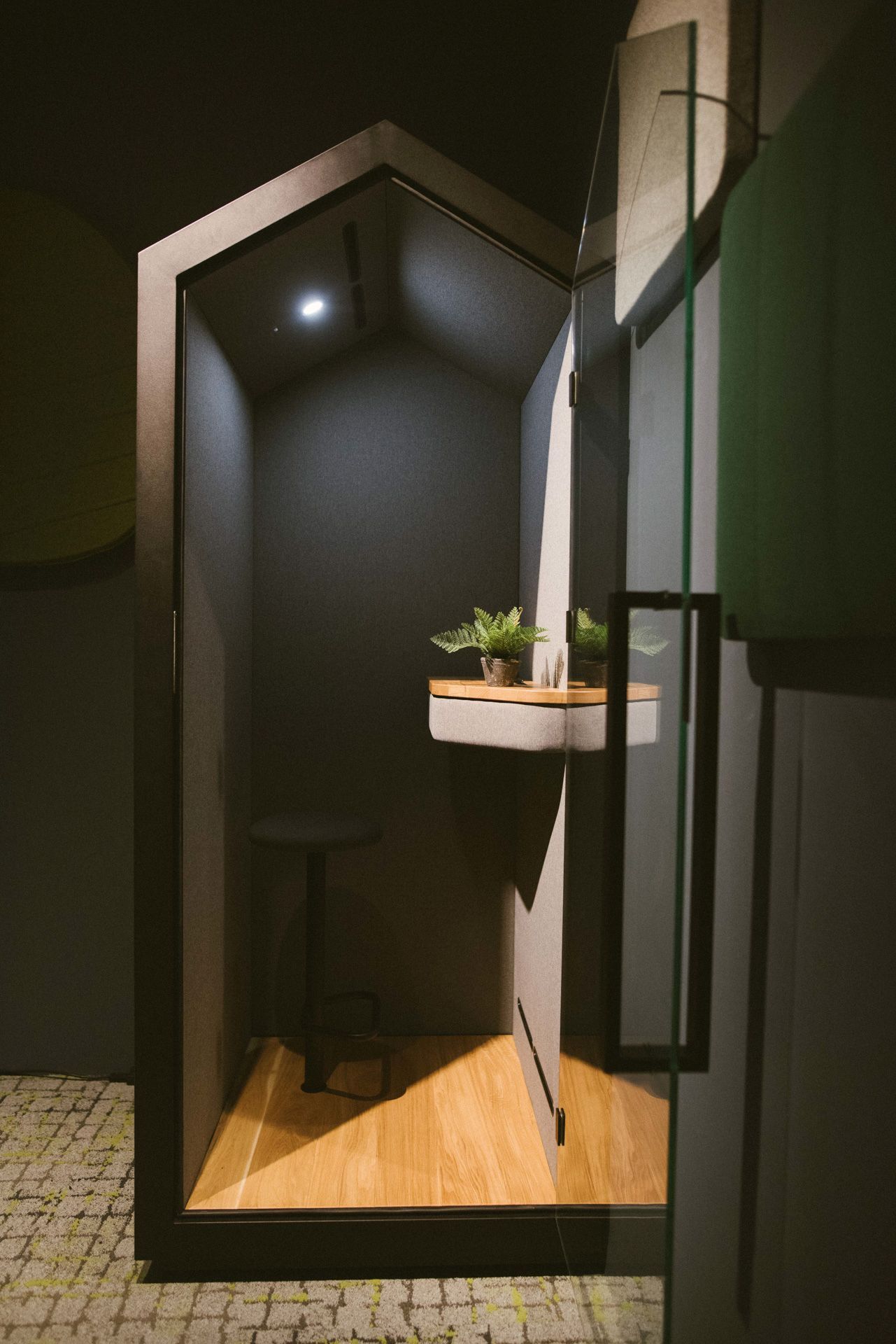 Bejot treehouse Akustikkabine mit Glastür, Hocker, Ablage und Pflanze für ungestörtes Arbeiten im Büro.