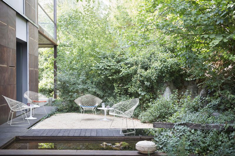 Drei Bertoia Diamond Sessel Outdoor von Knoll International im Garten mit Teich und viel Grün.